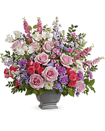 Love and Light - Spread love and light with this majestic rose bouquet, arranged in a classic footed urn. This bouquet includes pink roses, hot pink spray roses, ivory alstroemeria, purple carnations, miniature pink carnations, pink larkspur, lavender stock, white cushion spray chrysanthemums, purple sinuata statice, white limonium, leatherleaf fern, huckleberry and lemon leaf. 