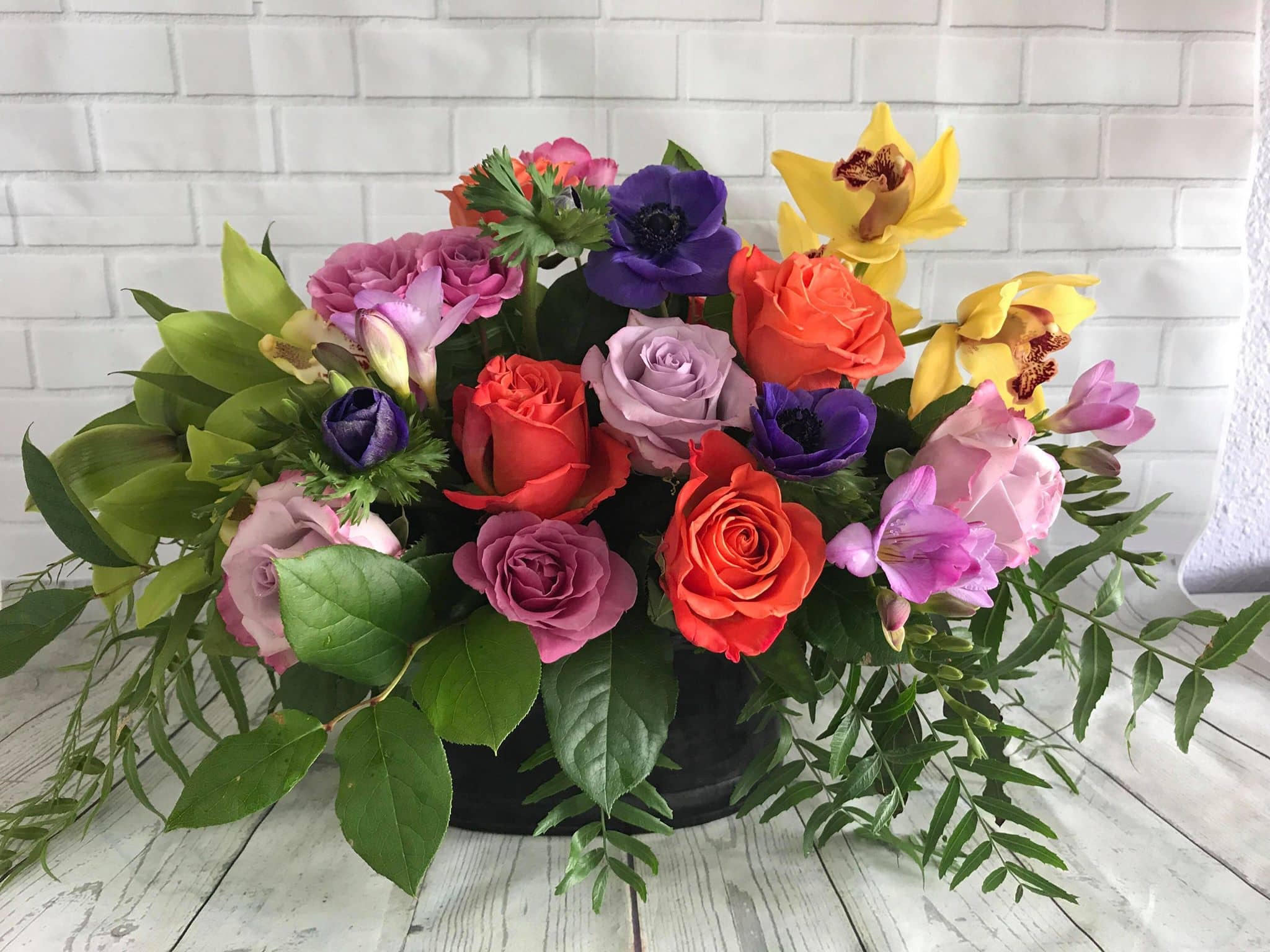 Beyond Brilliance - This elegant and vibrant flower arrangement features a stunning mix of roses, cymbidium orchids, and freesias in the brightest seasonal colors. Handcrafted by our expert florists, this luxury bouquet is perfect for birthdays, anniversaries, celebrations, or simply to brighten someone’s day with a bold splash of beauty.