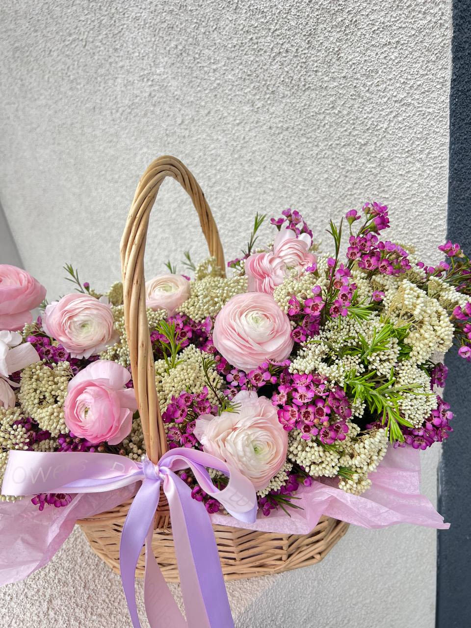 Poly - Poly  A romantic floral basket filled with delicate pink ranunculus and deep pink wax flowers — like a secret garden captured in bloom. Soft, textured, and naturally elegant, this arrangement speaks the language of affection and quiet charm.  Perfect for birthdays, love notes, or a thoughtful “just because.”  