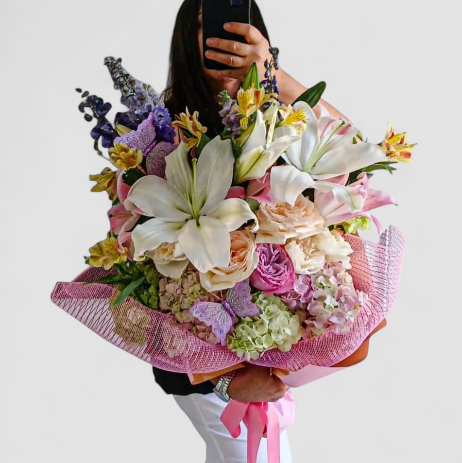 Rose Lily Fashion Bouquet Designer's Choice - Send this stunning grand size bouquet today to impress them and show them how much you care with it's pink and white blossoms roses lilies hydrangeas orchids and so much more wrapped in pretty pink paper with a long flowing ribbon bow. Gorgeous and perfect to send for every occasion to make their day. Send happiness.