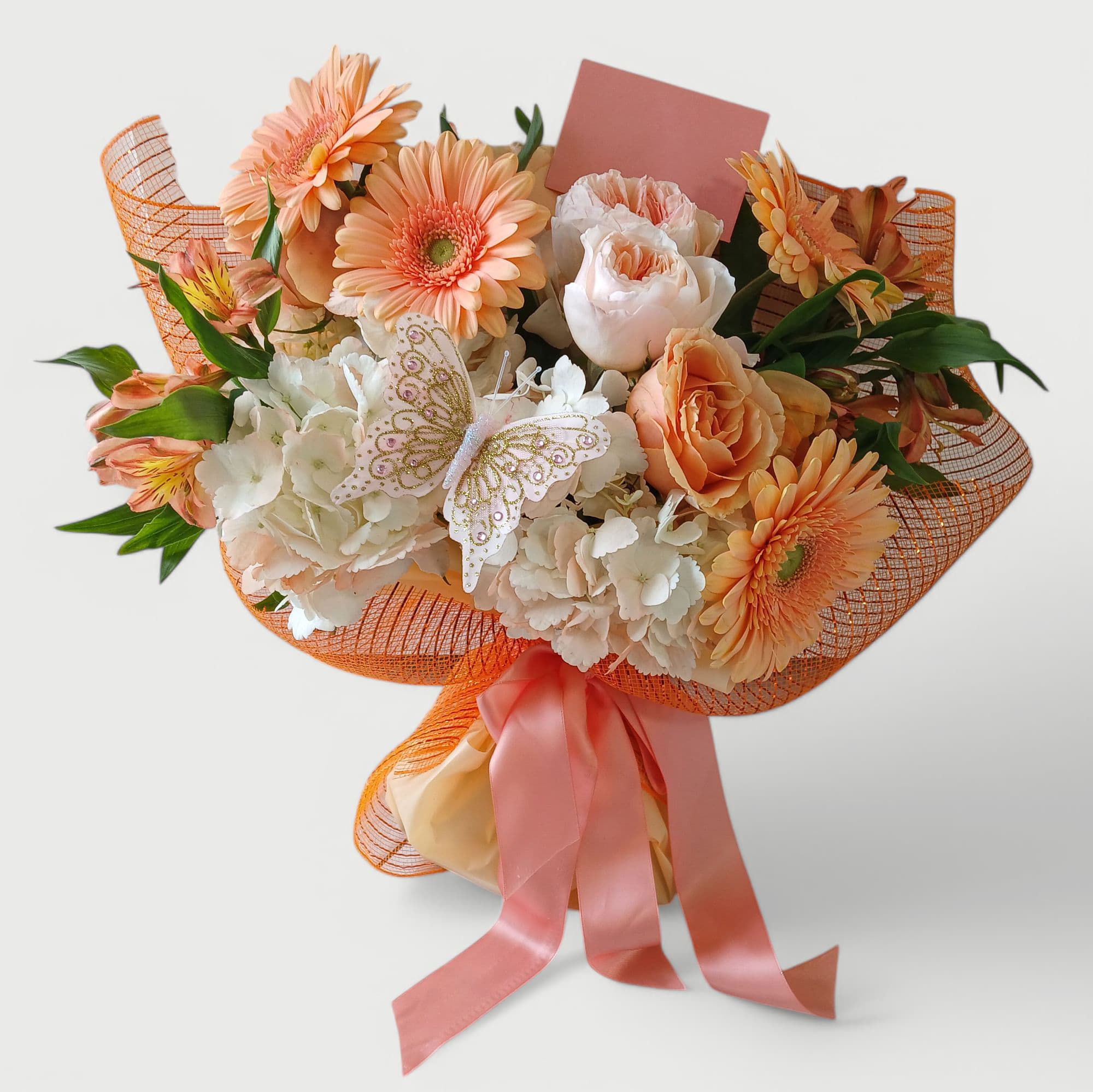 Peaches And Cream Rose Bouquet - Beautiful peach and vanilla roses hydrangeas daisies and more wrapped in pretty peach paper and mesh wrap with a lovely blush ribbon bow. Adorned with a sweet cheerful butterfly. Send her happiness with this beautiful bouquet.