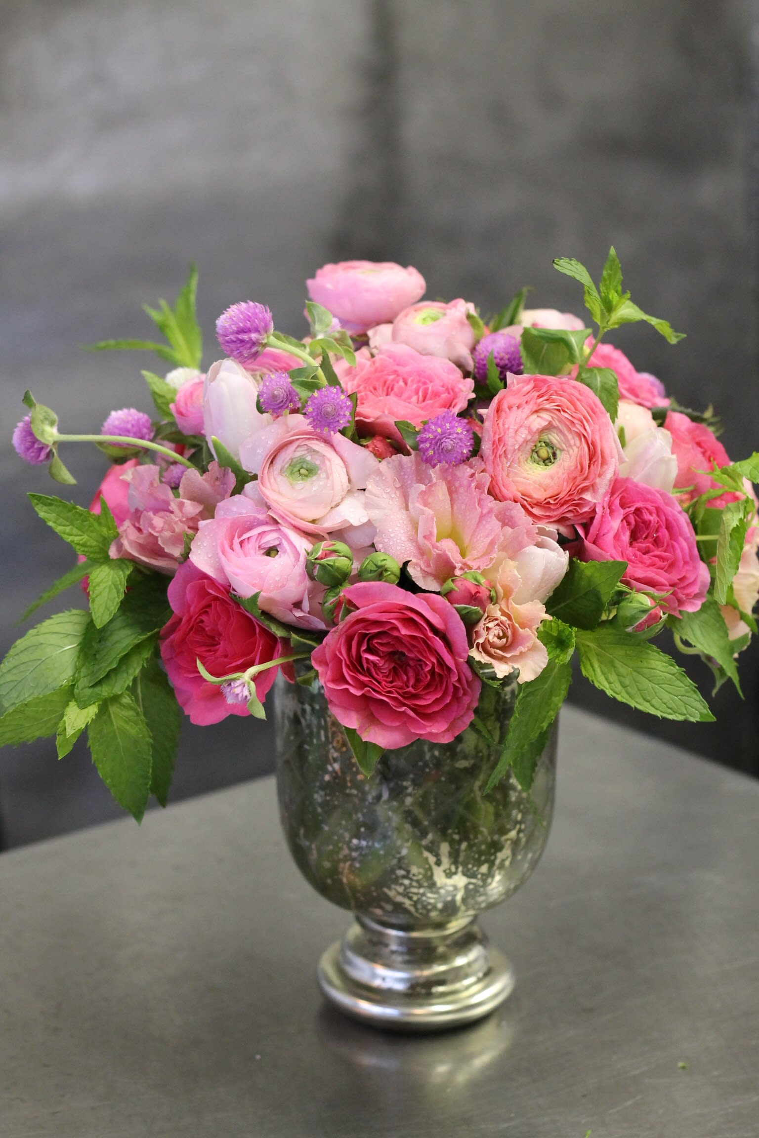Love Actually - Roses, ranunculus, lisianthus, mint and pretty foliage in cool mercury vase. Shown in deluxe vase. Gorgeous flowers in pretty vase. Send the best flowers in nyc. Same Day delivery available in Manhattan, Brooklyn, Bronx, Queens and Staten Island New York.