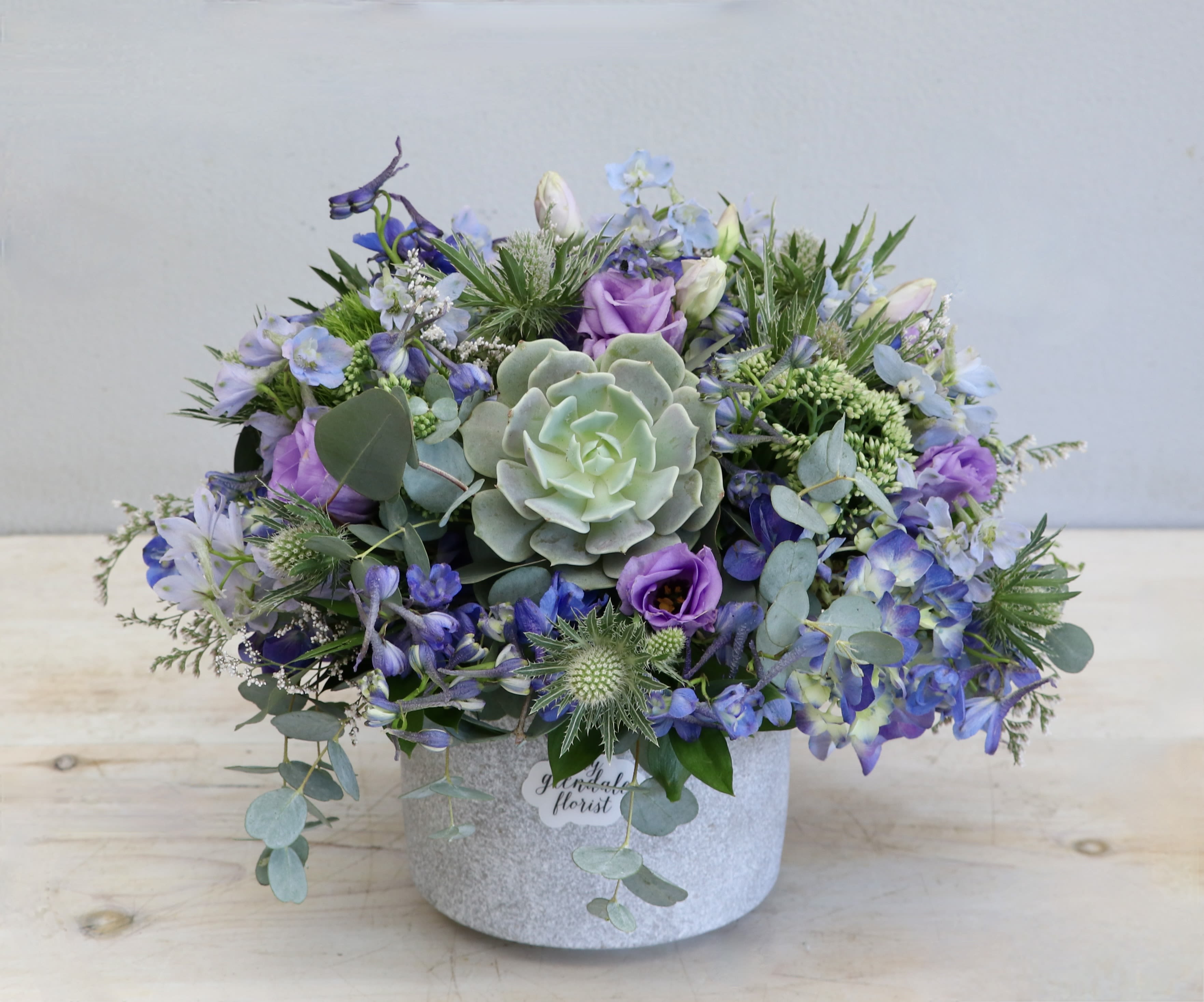 Forget Me Not - WeHo - With a mix of succulents, seasonal greens, and a sparkly vase, you're bound to make an impression this holiday season.   Standing about 10&quot; high, this arrangement makes for a special treat to the office on Valentine's Day.   Note that the second photo is the deluxe version of this arrangement. 