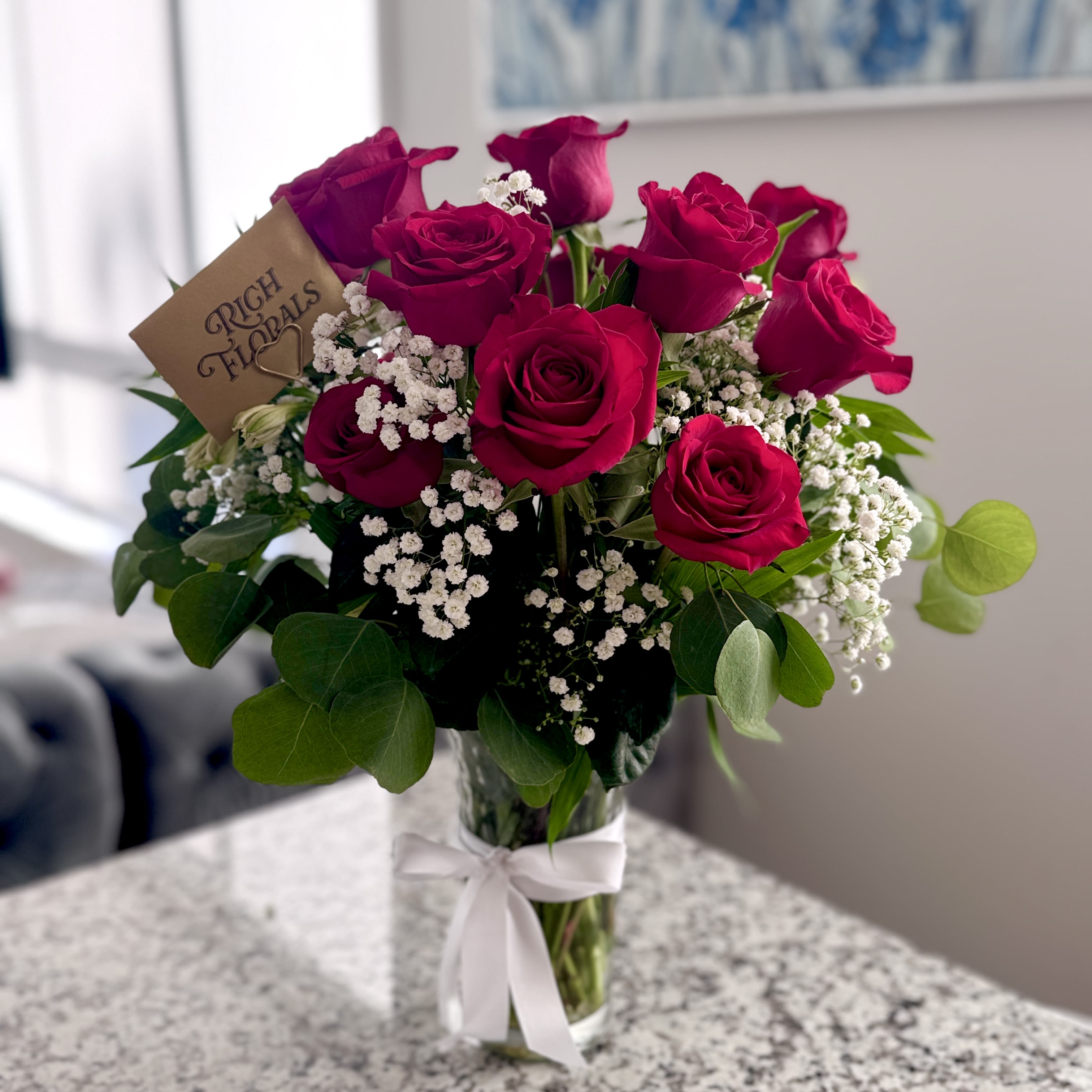 Long Stemmed Red Rose Arrangement - Dive into the classic beauty of our Dozen Long Stem Red Roses with baby's breath, each thoughtfully arranged in a timeless vase. These iconic blooms are symbols of love and devotion, with their deep red hues telling a story of profound affection. Ideal for conveying heartfelt emotions or marking memorable moments, this bouquet adds a touch of timeless charm to any celebration.  