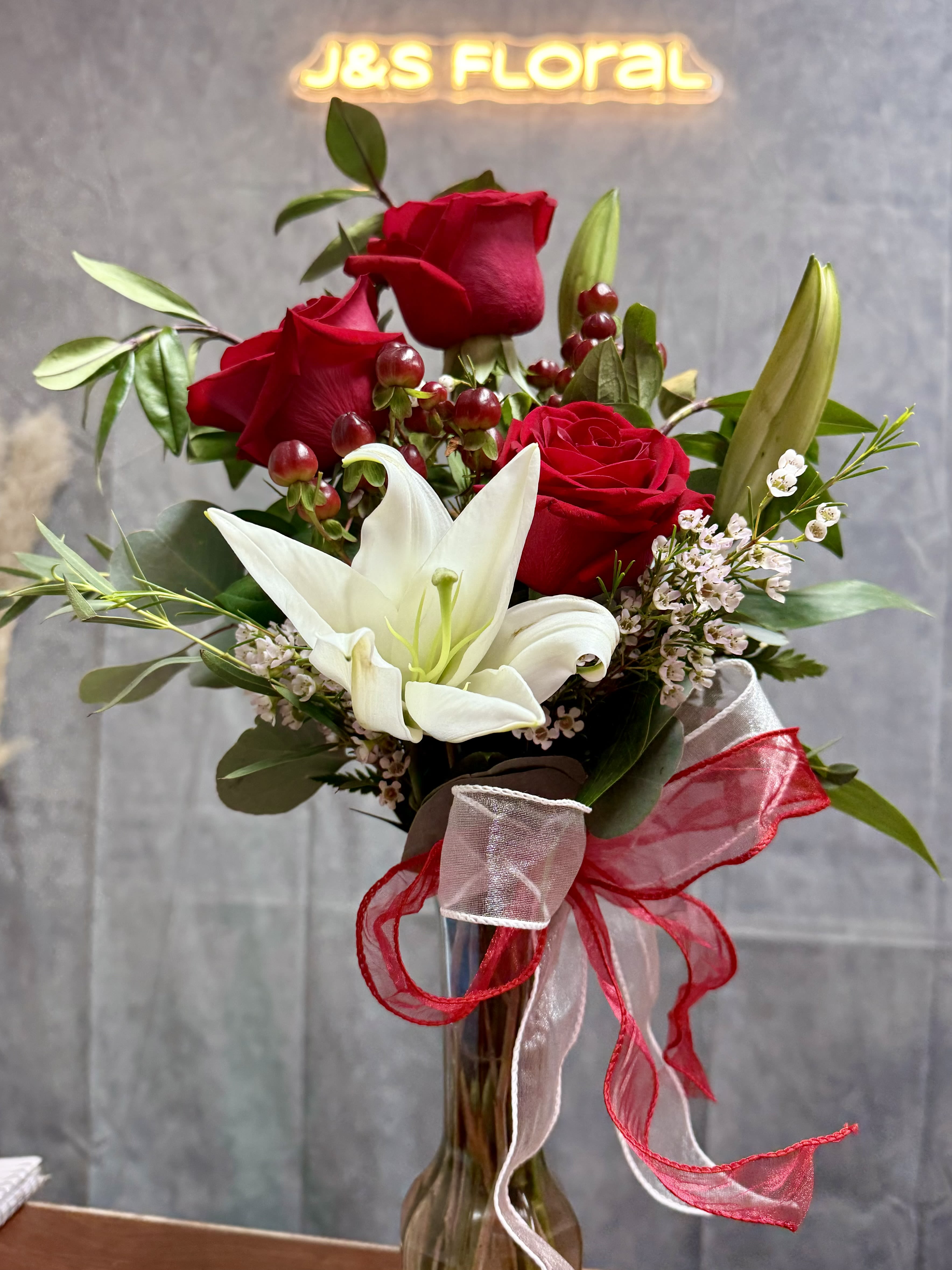 Cute in red - Three Red roses and a white lily , symbolizing love with timeless elegance.