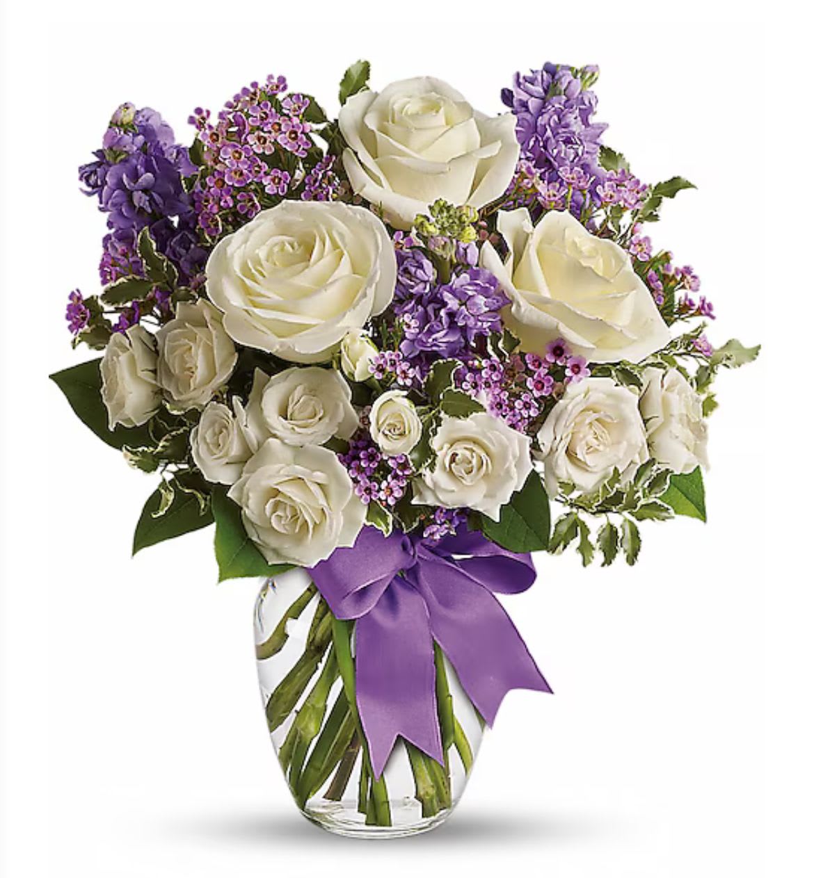 Enchanted Bouquet - A stunning bouquet featuring elegant white roses and delicate spray roses, complemented by fragrant lavender stock and charming wax flowers. The arrangement is gracefully displayed in a clear glass vase, tied with a lovely purple ribbon that adds a touch of sophistication and color coordination. Perfect for gifting or as a charming centerpiece! 