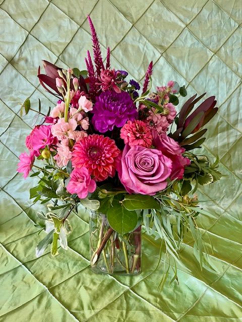EVENING SKY EVENING SKY - A glass cube filled with purple, coral, and peach tones just like the sunsets in late summer. Evening Sky is a garden style design comprised of dahlias, ranunculus, leucadendron, and eucalyptus in addition to other complimentary blooms.