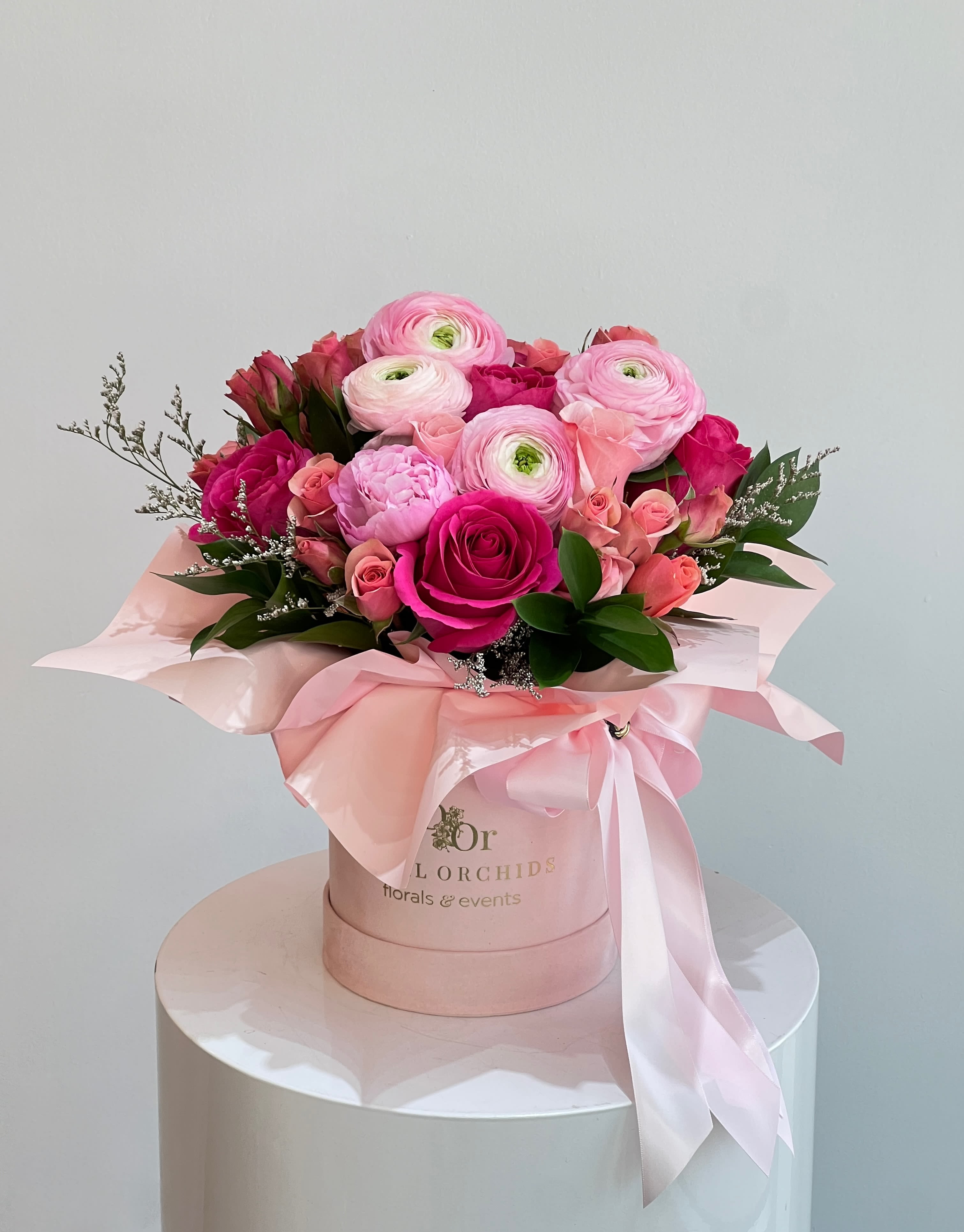 For My Babe ™ - This lush arrangement bursts with vibrant shades of pink, featuring rare peonies and ranunculus—coveted blooms prized for their layered, romantic petals. Paired with classic roses, spray roses, and touches of greenery, it’s elegantly gathered in a blush hatbox with flowing satin ribbons, making it a truly luxurious and unforgettable display.