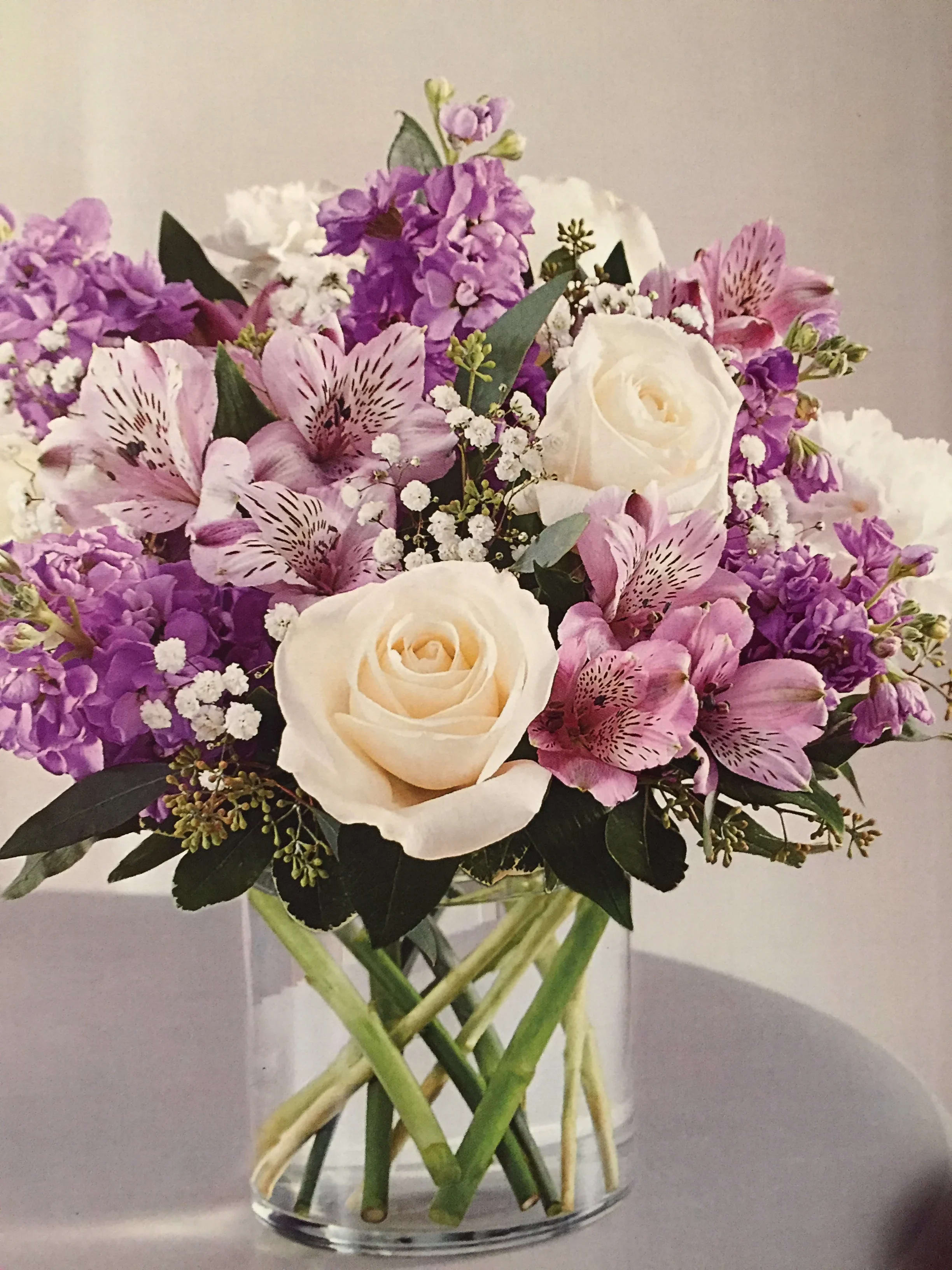 You're Special You're Special - This pretty arrangement has white roses, lavender stock and alstroemeria, baby breath and seed euk and greens in cube or 5" cylinder vase and lavender bow.5