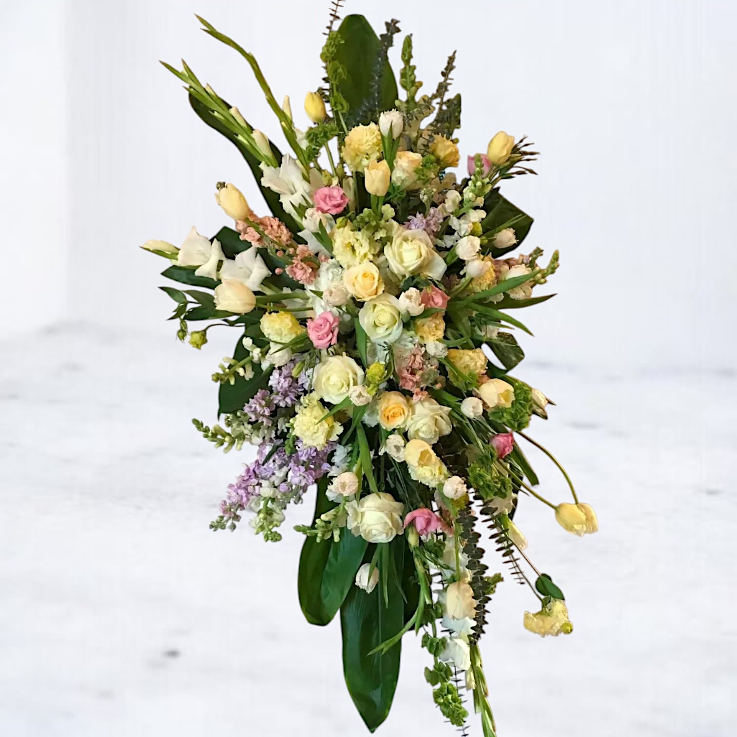 Dawnlight Remembrance Standing Spray - Honor a gentle spirit with the serene beauty of our Dawnlight Remembrance Spray. Designed with a soft cascade of pale yellow roses, white lilies, tulips, lisianthus, and pastel accents, this graceful standing spray offers a peaceful expression of sympathy. Ideal for memorials, celebrations of life, and funeral services, its elegant vertical silhouette creates a radiant focal point that feels both hopeful and heartfelt. Available for delivery to funeral homes and cemeteries across Houston, Willis, Magnolia, and surrounding areas.  