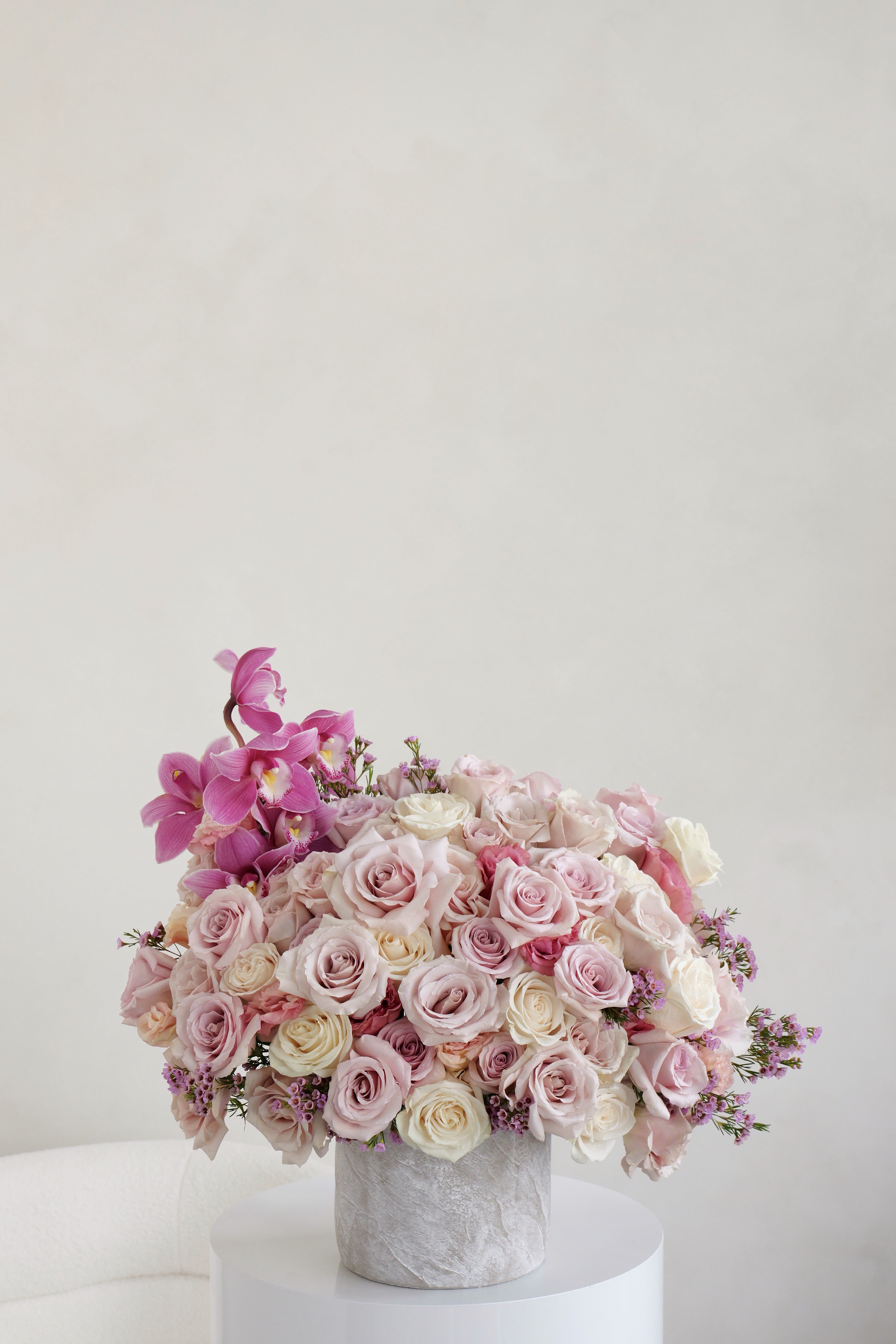Amara Amara - A lovely mix of soft blush and ivory roses with a bright touch of magenta. This arrangement is perfect for any occasion and adds a sweet, elegant touch to any room.