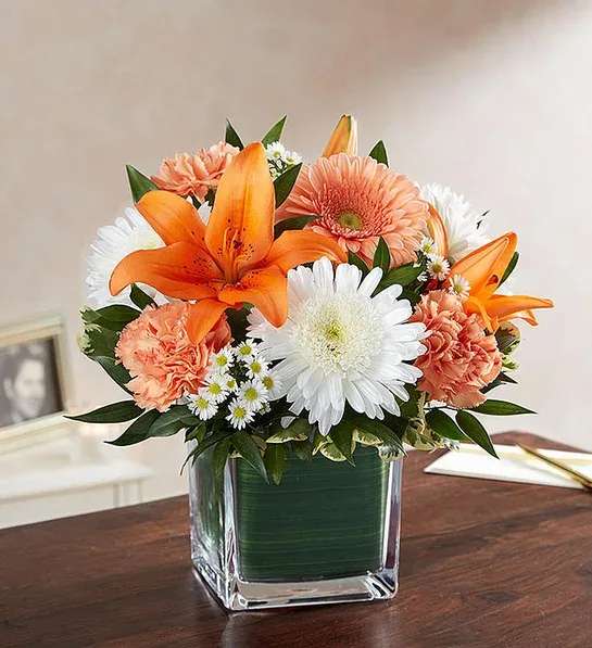 Healing Tears Healing Tears - Our arrangement of peach roses, daisies, orange lilies and white roses, expertly gathered in a clear glass cube lined with a Ti leaf ribbon, makes for a sweet and sentimental gesture of remembrance and healing.