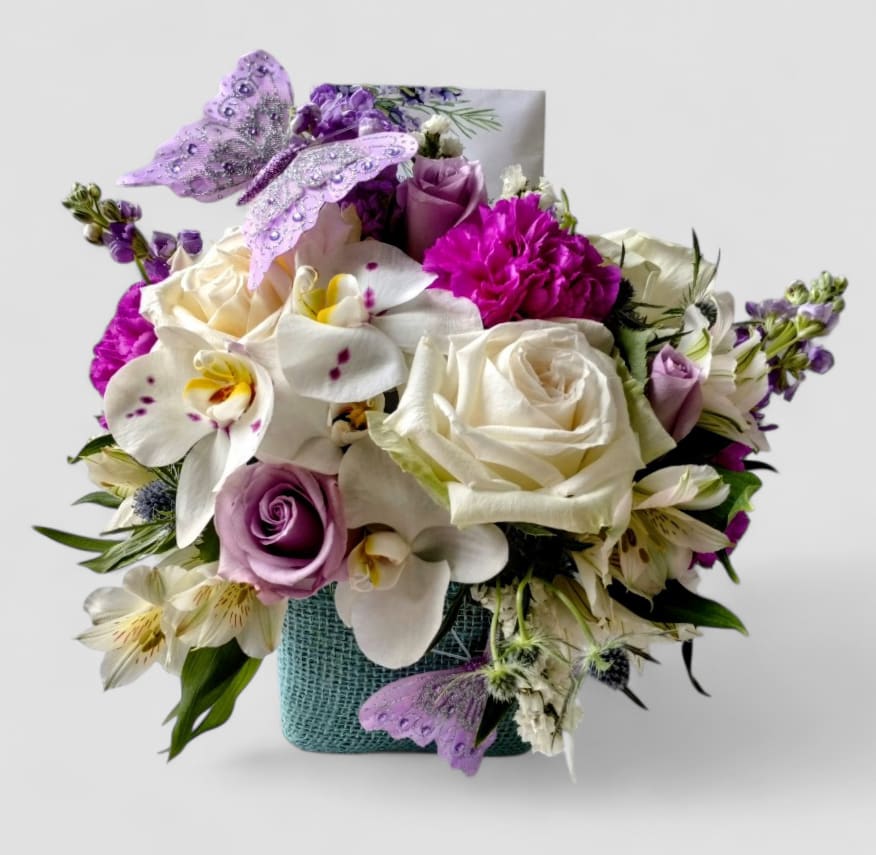 Lavender And Vanilla Rose And Orchid Blossoms Condolences Beauty Designer's Choice - Lovely roses orchids and more arranged in a modern glass cube vase wrapped in beautiful pale blue jute ribbon. Perfect for a condolences. All fresh flower bouquets that leave my flower shop studio are beautiful works of art made special each time. Send them your deepest condolences.