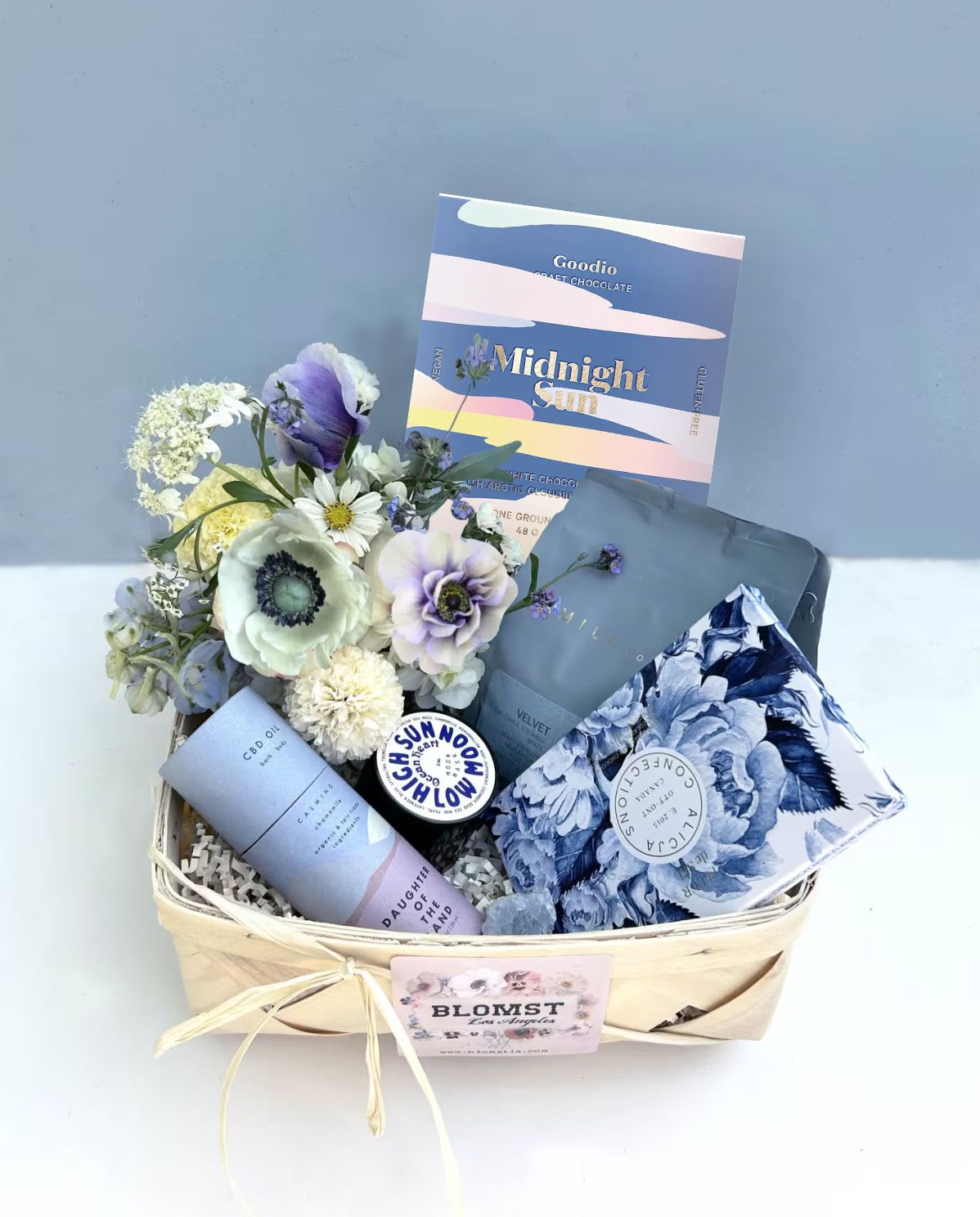 Blue velvet Basket - vegan - Gorgeous basket full of healthy vegan treats, planet friendly beauty products and gifts. Perfect for any day that deserves a great gift. In the basket: Lamill VELVET coffee blend. Full bodied with lots of chocolate and caramel sweetness with mild fruit notes. Goodio bar: white chocolate topped with Arctic cloudberry crumble. Nothing shines brighter than the midnight sun. Taste the feeling of endless light. Dairy-free, gluten-free and soy-free. Alicja Confections Fleur de Sel 54.5% dark chocolate bar. Sweet and silky dark chocolate with sea salt. High Sun Low Moon natural face mask &quot;Ocean Heart&quot;. This mask is deeply cooling, hydrating,  pore reducing, intuitively balancing, brightening, age-embracing, subtly exfoliating, blemish reducing, anti-microbial &amp; bacterial. It creates a fresh glow of supple nourished skin for all skin types. High in naturally occurring minerals and oceanic superfoods. Daughter of the Land Chamomile CBD oil. The oil is a highly potent bath + body CBD oil formulated to soothe muscles, joints, and skin, in and out of the tub. Perfect for those with sensitive skin since this blend contains zero essential oils which can irritate sensitive skin, and just a hint of sweet chamomile extract.  You can apply a dropperful of oil directly to an area in need and/or in the bath for a break from it all. Blue calcite crystal - helps w emotional healing, promotes feelings of relaxation, tranquility, and peacefulness. Placed in a wood braided basket, 9&quot; by 9&quot;.