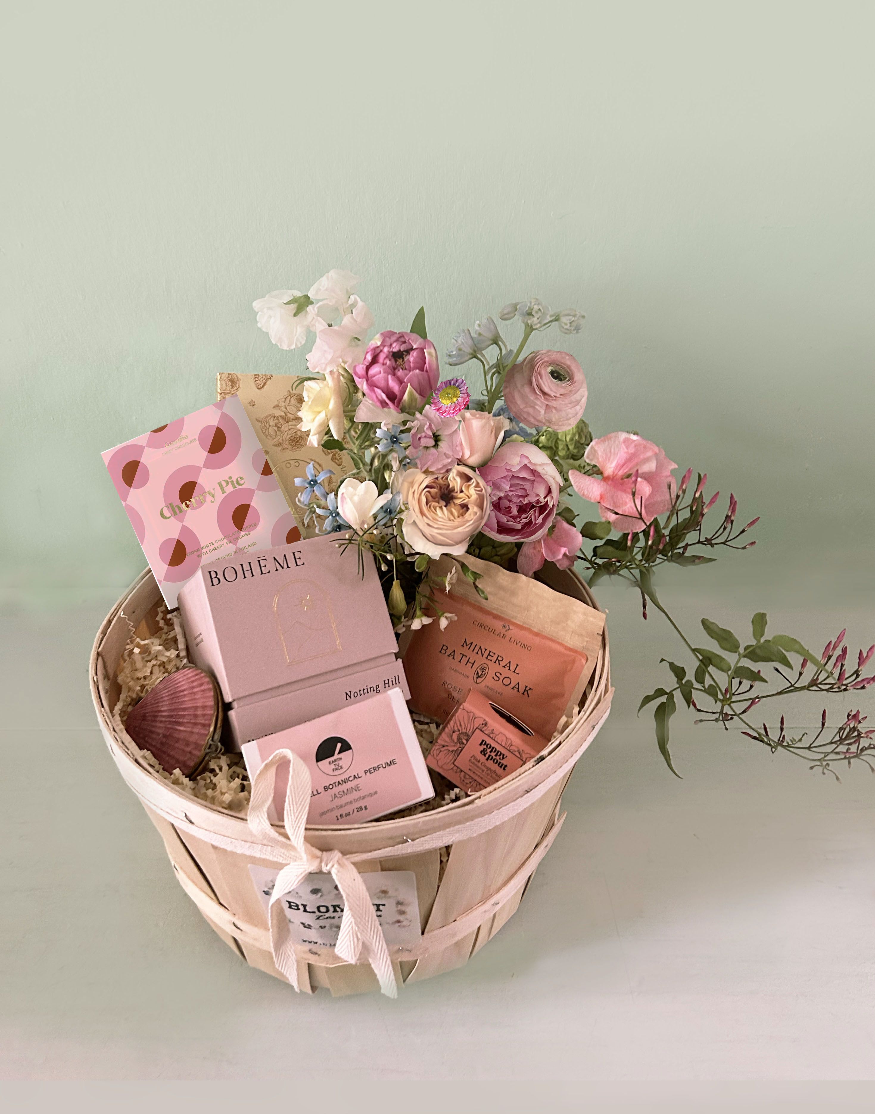 Lola Luxe Basket - Premium sustainable luxury in this packed, gorgeous and unique basket full of organic, clean, eco friendly, natural beauty products, Blomst flowers and lovely vegan chocolate. Created to give to a special someone who will enjoy botanical and organic luxury - all in one pretty, eco friendly basket. Adorned with a natural shell with solid, botanical perfume! So cute. The basket contains: - Blomst arrangement (3 by 3 clear vase w/ Blomst signature flowers) - Earth Tu Face pure botanical balm perfume in a real sea shell. (organic cold-pressed safflower, beeswax, and sunflower-derived vitamin E make up the base of this solid perfume. Aroma of real Jasmine blossoms, oils of Jasmine Grandiflorum and Jasmine Sambac) - Poppy and Pout flower powered Pink Grapefruit natural lip balm - Circular Living Rose petal and Geranium bath soak. A luxurious mineral soak for sore muscles with rose, geranium, and lemon to balance the skin and cleanse the mind and body. - Boheme &quot;Notting Hill&quot; natural candle: 8.5 oz | 240 g. All Natural Wax. Clean Burning. Vegan. Cotton Wicks. Burn time approximately 50 hours. Phthalate Free. Sustainable. Handmade in the USA Goodio vegan Cherry Pie Organic White Chocolate.  - Alicja Confections vegan dark chocolate bar &quot;Afternoon Tea&quot;