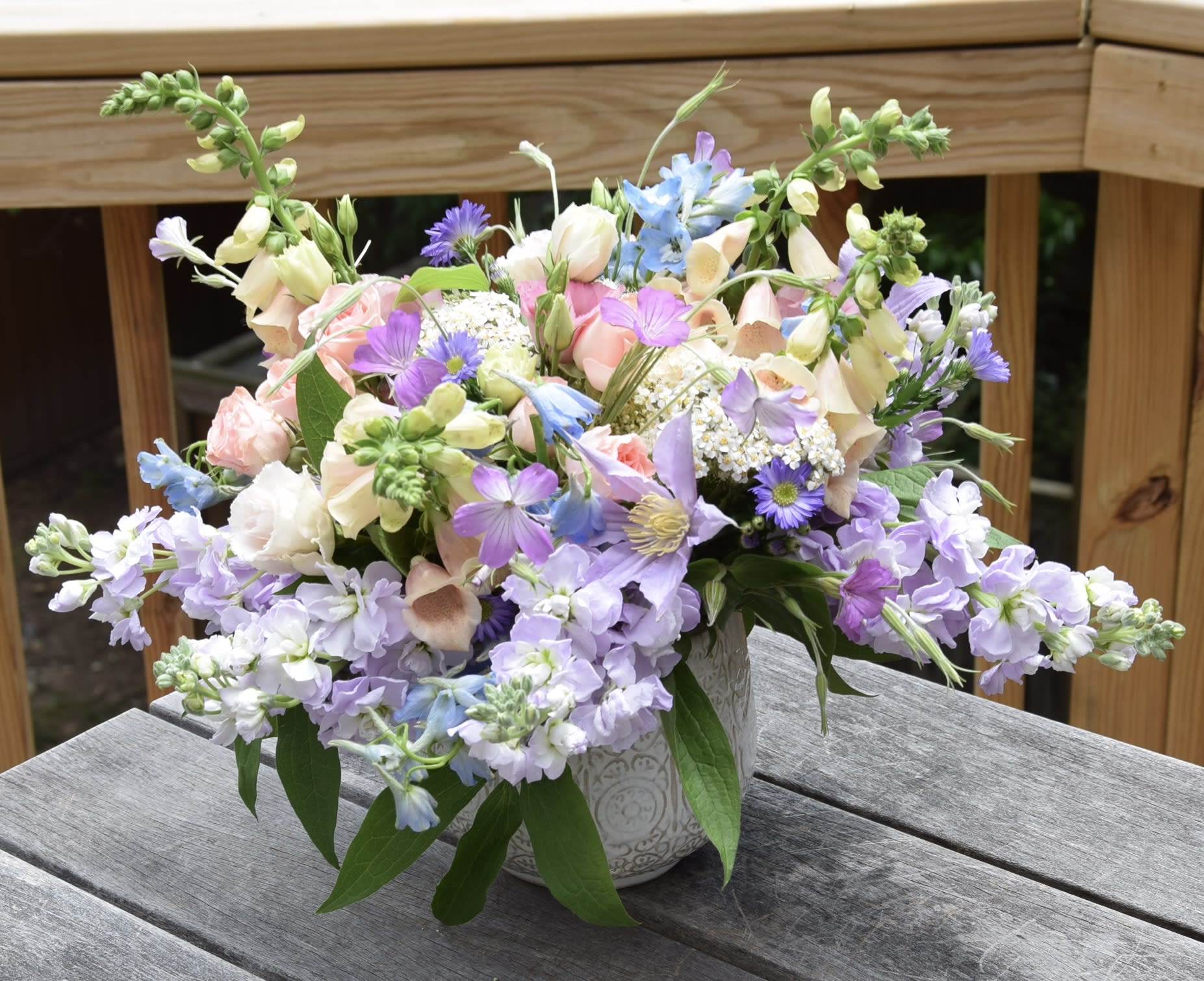 Fairy's Garden - A lovely arrangement in a garden style with seasonal flowers in spring pastel color tones, arranged in a ceramic vase. The usual mix includes stock, snap dragons, tulips, clematis, lisianthus, ranunculus and more, based on the availability.  