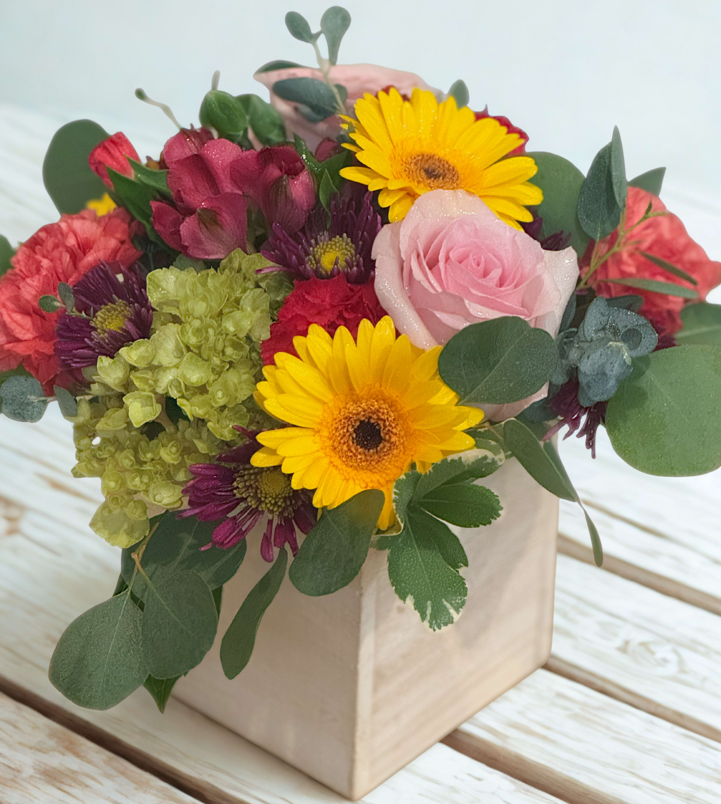 Joyful Bouquet -  This cheerful and compact bouquet is a delightful burst of color, combining the sunny disposition of yellow gerbera daisies with an inviting mix of red, pink, and vibrant green blooms. Its lively arrangement is perfect for brightening any space and bringing a smile.