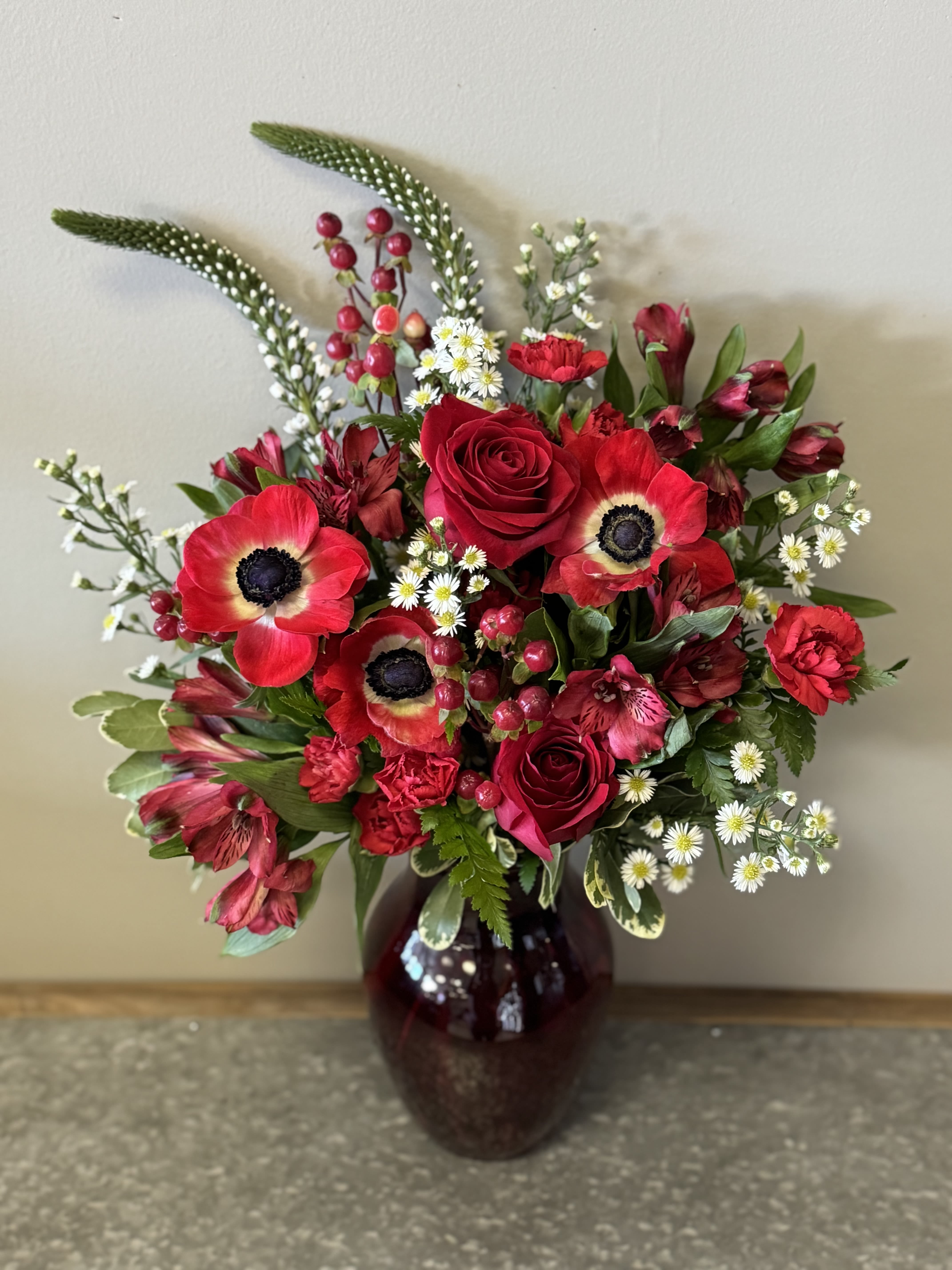 July Ruby Bouquet - Birthstone Collection What better way to celebrate your loved one's birthday than with our July Ruby Bouquet! Hand-designed with a stunning gathering of vibrant reds and white blooms, lush greenery and in a ruby vase, it’s a thoughtful sentiment filled with the passion and power of a ruby stone.  ATTENTION! If you are ordering this arrangement on a different month other than what it's respected month is, there will be substitutions for certain flowers depending on seasonal availability. We will stay within the same color scheme and design style!  PLEASE NOTE: Florist reserves the right to make modifications to the design based on seasonality and accessibility of blooms and vases. Any modifications made will honor the palette, intent, and feeling of the pictured design. Contact floral designer directly with any specifications or concerns.