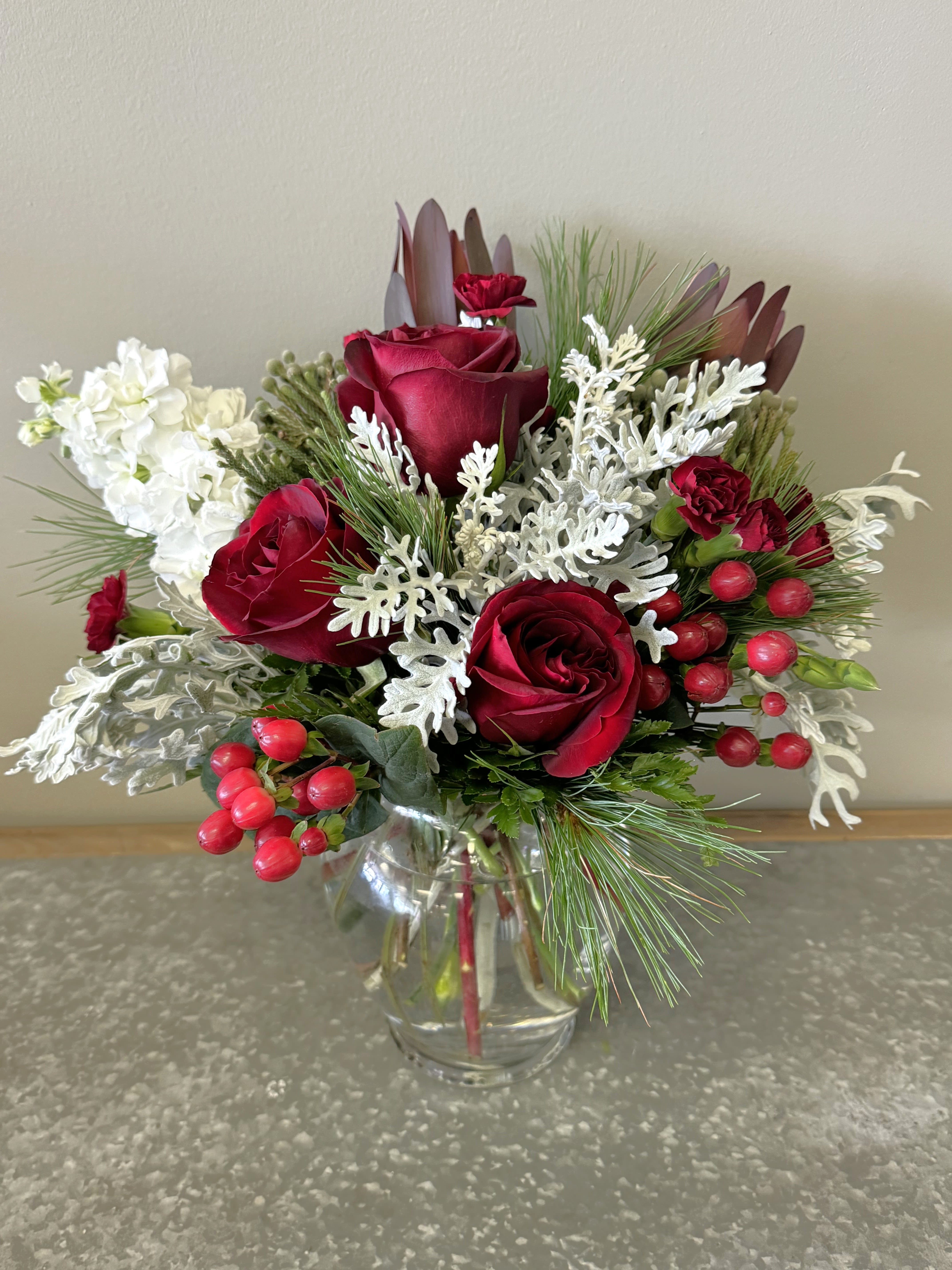 January Garnet Bouquet - Birthstone Collection What better way to celebrate your loved one's birthday than with our January Garnet Bouquet!  Hand-designed with a lush gathering of burgundy blooms, evergreens and silver touches, it’s a thoughtful sentiment filled with the deep, rich beauty of a garnet stone.  ATTENTION! If you are ordering this arrangement on a different month other than what it's respected month is, there will be substitutions for certain flowers depending on seasonal availability. We will stay within the same color scheme and design style!  PLEASE NOTE: Florist reserves the right to make modifications to the design based on seasonality and accessibility of blooms and vases. Any modifications made will honor the palette, intent, and feeling of the pictured design. Contact floral designer directly with any specifications or concerns.