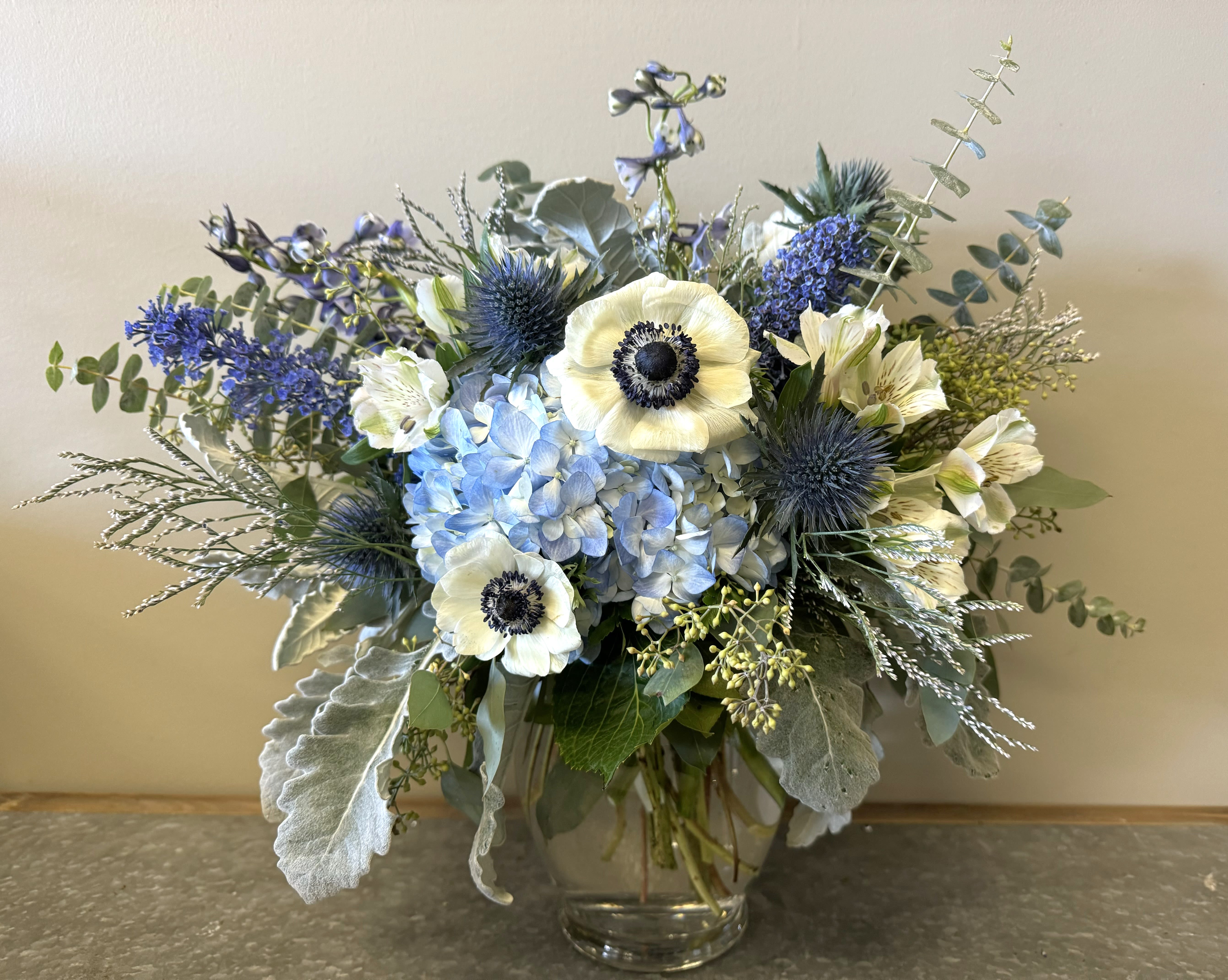 March Aquamarine Bouquet March Aquamarine Bouquet - Birthstone Collection What better way to celebrate your loved one's birthday than with our March Aquamarine Bouquet! Hand-designed with a stunning gathering of light blue and white blooms, lush greenery and silver touches, it’s a thoughtful sentiment filled with the cool and calming beauty of an aquamarine stone. ATTENTION! If you are ordering this arrangement on a different month other than what it's respected month is, there will be substitutions for certain flowers depending on seasonal availability. We will stay within the same color scheme and design style! PLEASE NOTE: Florist reserves the right to make modifications to the design based on seasonality and accessibility of blooms and vases. Any modifications made will honor the palette, intent, and feeling of the pictured design. Contact floral designer directly with any specifications or concerns.