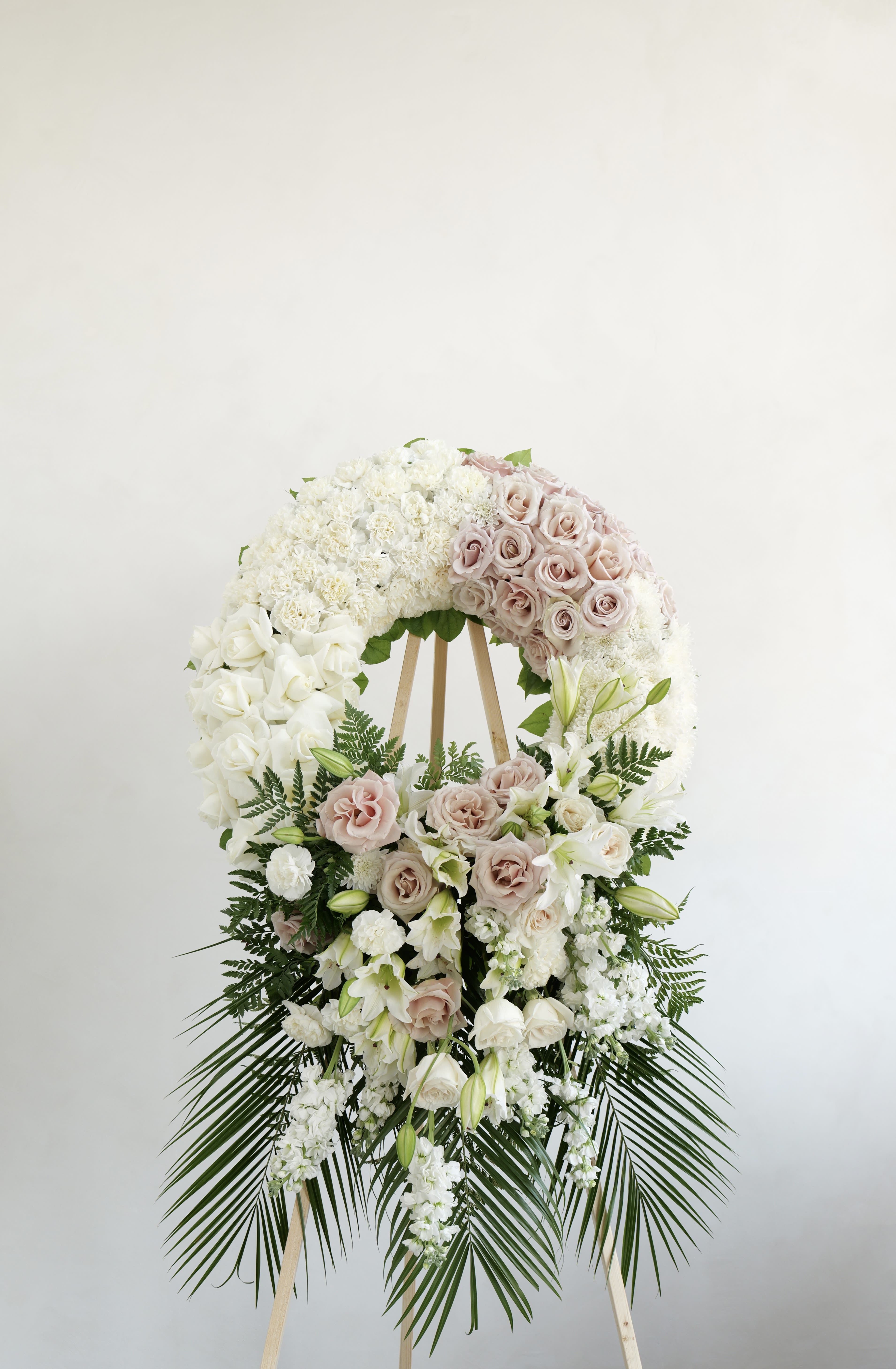 Wreath No. 01 Wreath No. 01 - A classic standing wreath thoughtfully designed with soft, elegant blooms to honor the memory of a loved one. Featuring a graceful blend of white flowers for peace and purity, paired with blush-toned roses for warmth and remembrance, this arrangement offers a timeless expression of sympathy. Accented with lush greenery, it conveys comfort, respect, and everlasting love.