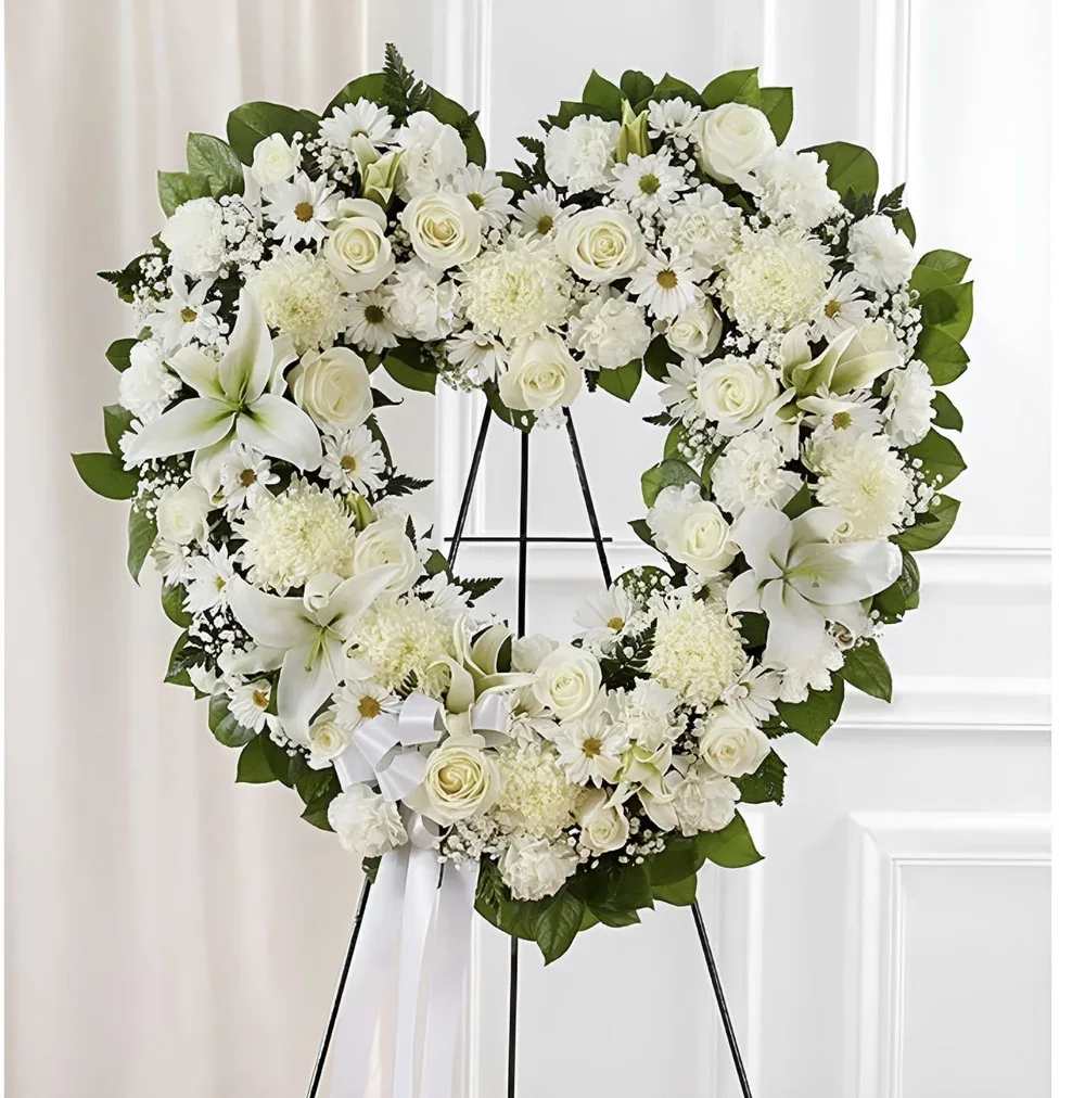 Open Hearth White Open Hearth White - Crafted in the shape of an open heart, this arrangement symbolizes enduring love. The ring of flowers offers a tender way to remember cherished moments. Displayed on an easel, it shares a heartfelt message of remembrance.
