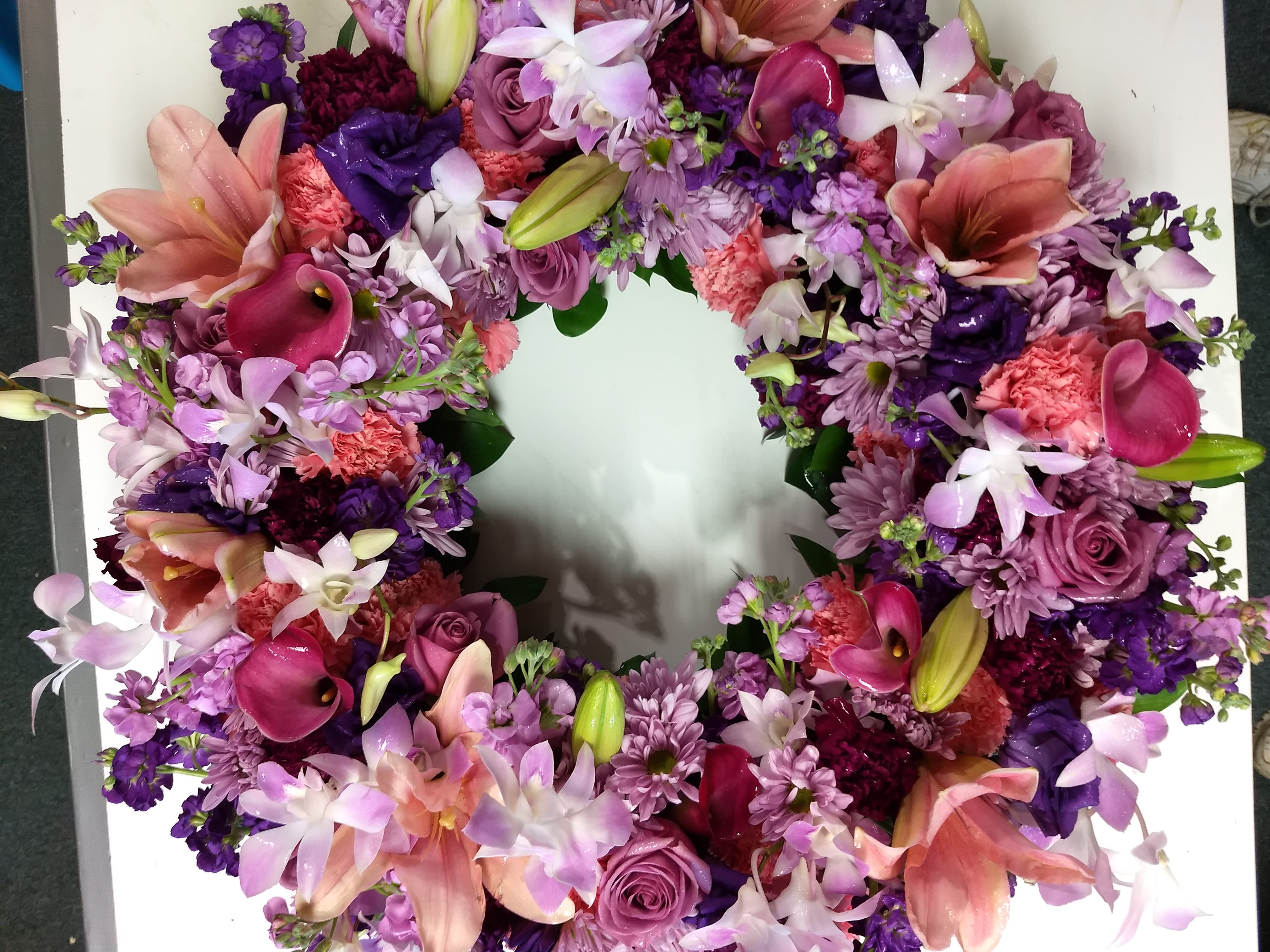 Cricket's Sleep in Peace wreath - Sleep in Peace Wreath A sweet and colorful tribute, this wreath features a soothing blend of lavender blooms, pink Asiatic lilies, lavender chrysanthemums, pink and purple carnations, lavender roses, dendrobium orchids, lisianthus, calla lilies, and stock. Beautifully arranged to offer comfort and honor the peaceful rest of a cherished soul.   **** Please note: 48 hour notice MAYBE REQUIRED We custom-design this arrangement using best-of-day seasonal flowers. This image is a general representation of its size and style and may not feature the exact flowers shown. Due to disruptions in the global supply chain and staff shortages, we may have to make last minute substitutions to your selected design. If we need to make significant changes we will call you first to get your approval*** Thank you for understanding.