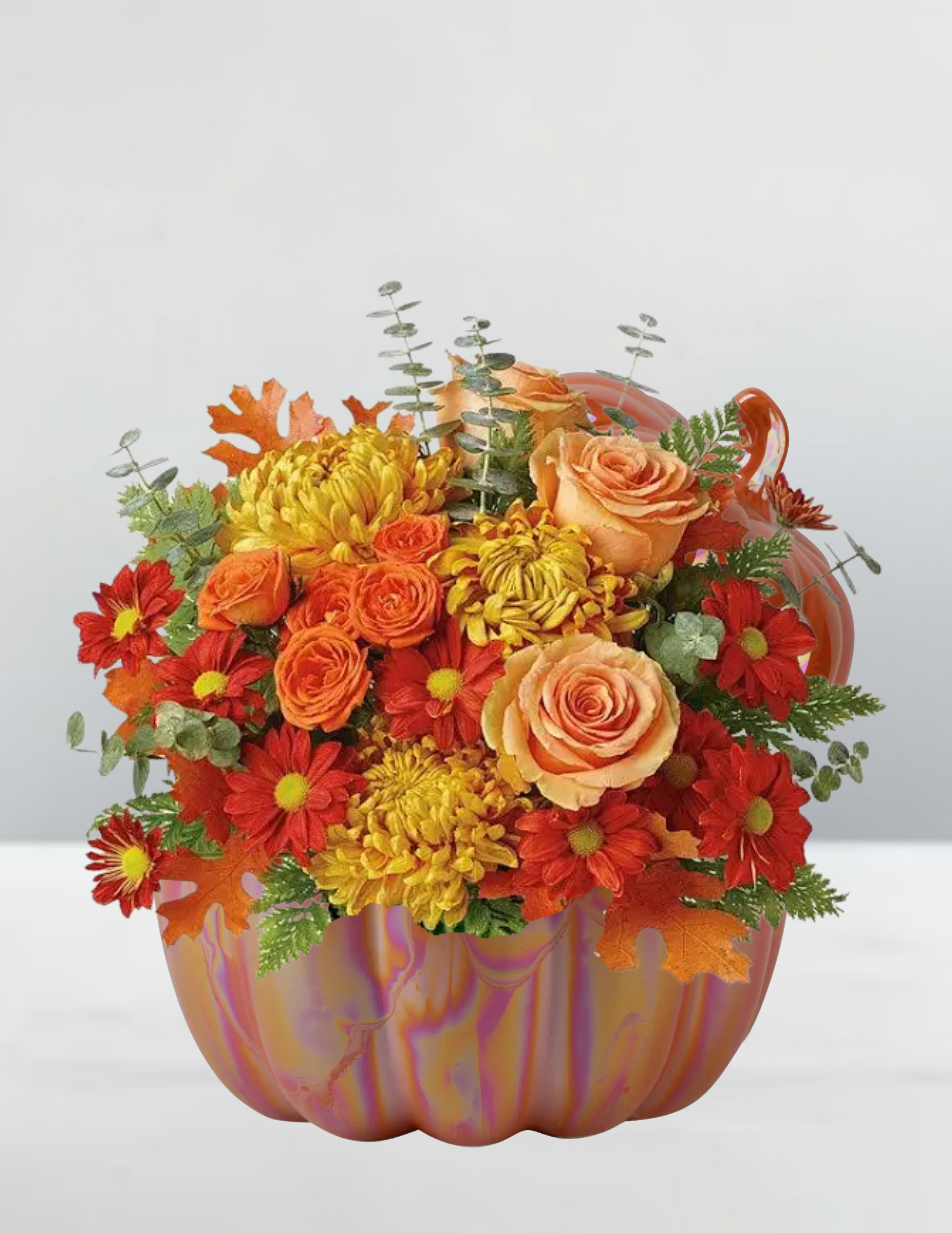 Pumpkin spice blooms  - Cozy up with the warmth of fall with our Pumpkin Spice Blooms arrangement! This vibrant bouquet features a mix of orange roses, yellow chrysanthemums, and red daisies, all nestled within a beautiful marbled pumpkin vase. Accented with greenery and a few autumn leaves, this arrangement is the perfect way to bring the flavors and feelings of the season into your home. The pumpkin vase adds a playful touch, making it a unique and eye-catching centerpiece for any room. Order now and get ready to fall in love with the beauty of the season!