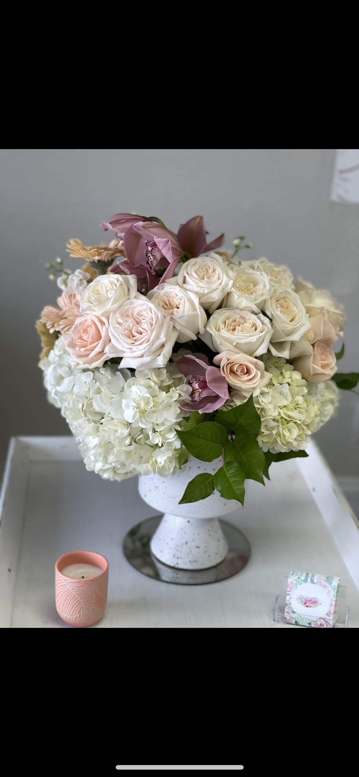 WOW - A unique urn style white vase with gold specks FILLED with White hydrangea Cymbidium orchid’s garden roses fringe roses and stock with a few Gerber Daisy’s 
