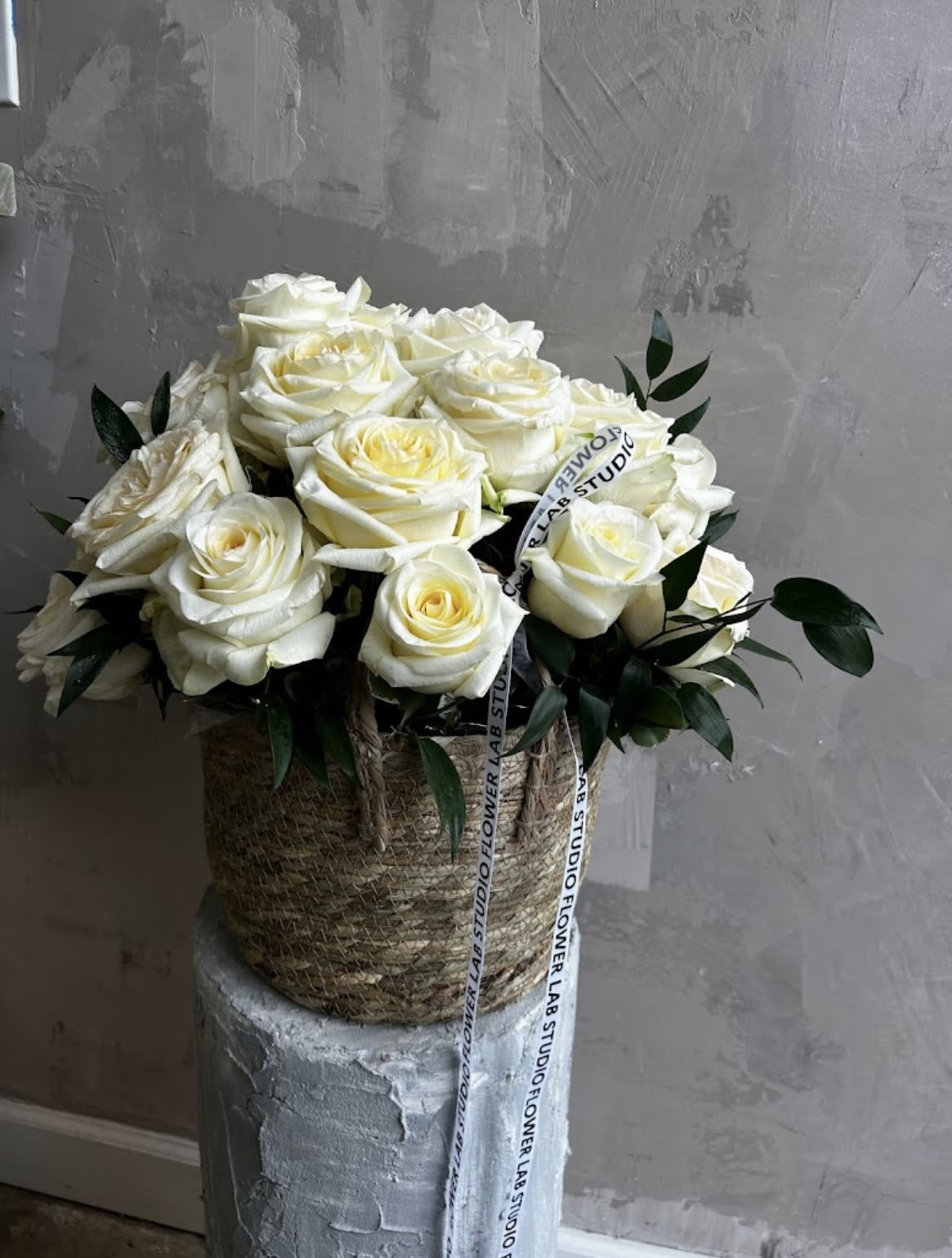 Eternal Ivory Roses  - A timeless arrangement of velvety white roses, styled in a woven basket. Accented with lush greenery, this design embodies grace, purity, and sophistication- perfect for weddings, anniversaries, or simply making a grand impression. 