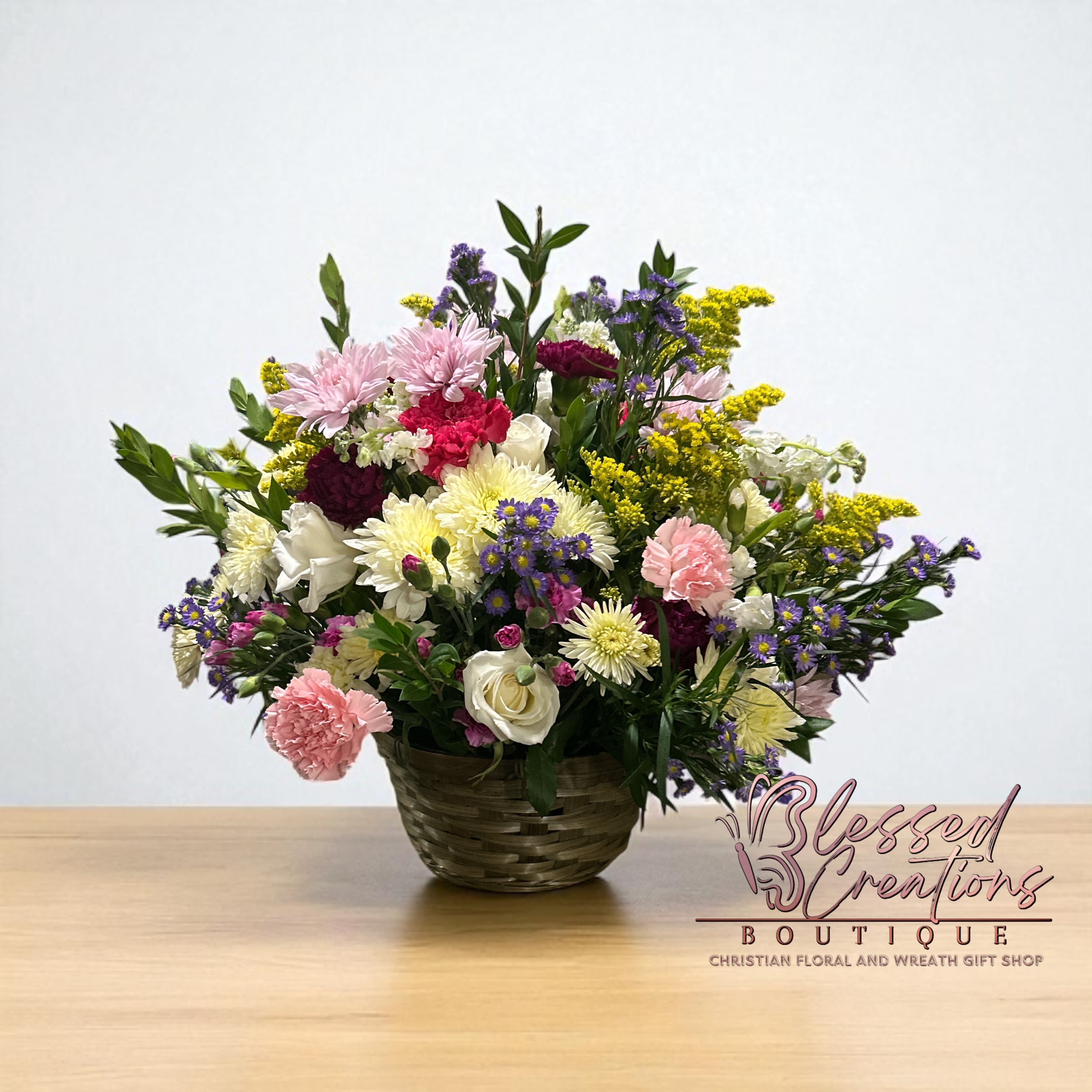 Garden Harmony Basket  - A lush garden-style basket featuring white, pink, purple, and yellow blooms with greenery, designed to bring cheer and beauty. A wonderful gift for sympathy, home, or church services.