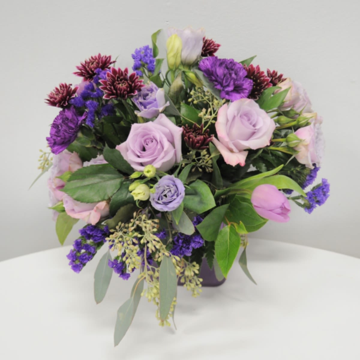K110 Purple Embrace K110 Purple Embrace - A Realm of Floral Enchantment Step into elegance with Purple Embrace, a refined take on our beloved Purple Passion. Presented in a sleek lavender glass cube, this arrangement blends modern luxury with timeless charm. At its heart, lavender roses bloom like whispered secrets, symbolizing grace and enchantment. Complemented by exquisite purple and lavender flowers, each petal tells a story of gentle sophistication. Lush-seeded eucalyptus drapes effortlessly, adding texture and depth to this captivating bouquet. Hand-selected blooms create a composition that radiates refined opulence.