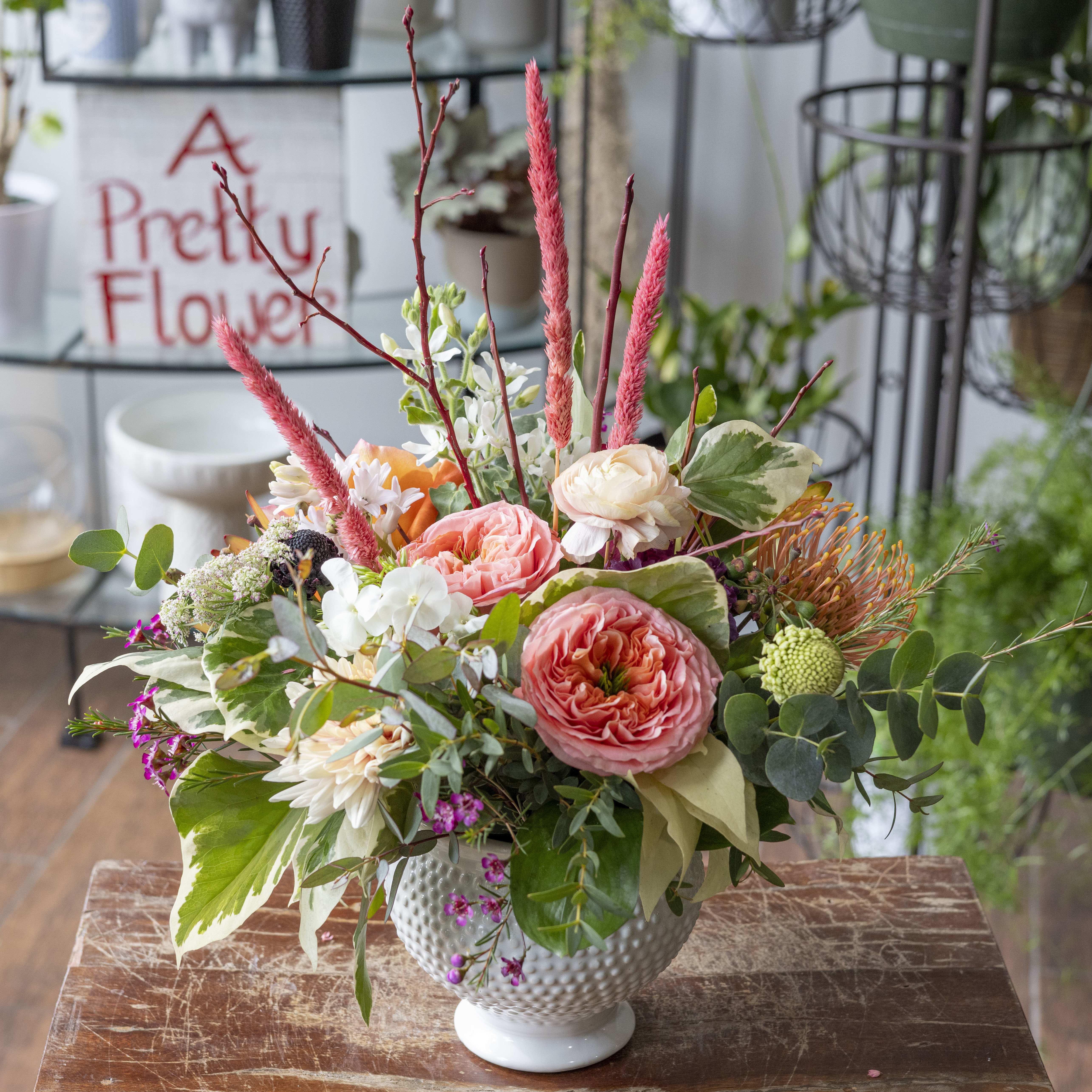 Alessandra - Variety of blooms and interesting textures in a white ceramic vase.