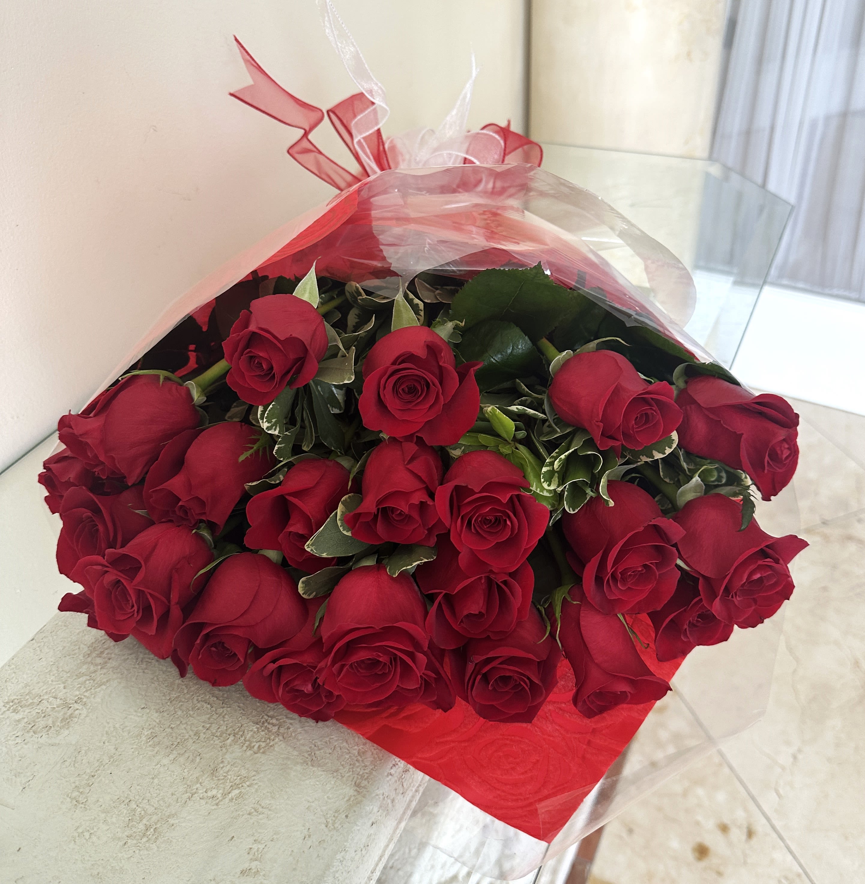 24 Red Roses wrap Bouquet long stem arranged with greenery and a bow. - 24 Red Roses Long Stem wrapped bouquet with greenery and a bow.