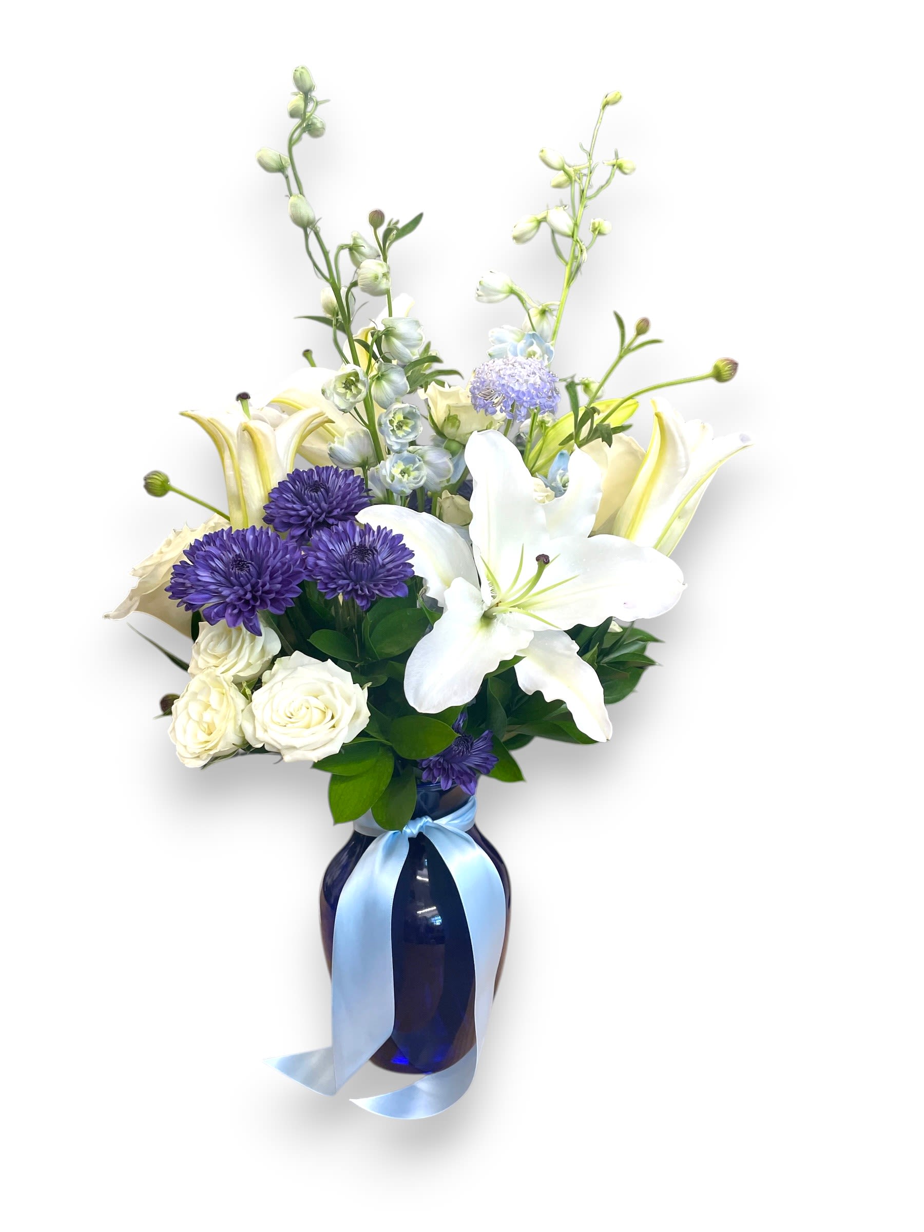 Blue Serenity Vased Arrangement - Express your deepest condolences with the serene beauty of the &quot;Blue Serenity&quot; bouquet. Featuring elegant white lilies, delicate blue delphinium, and vibrant purple asters, all thoughtfully arranged in a graceful vase with a soft blue ribbon. This calming arrangement offers a peaceful tribute, embodying comfort, grace, and heartfelt sympathy during difficult times.