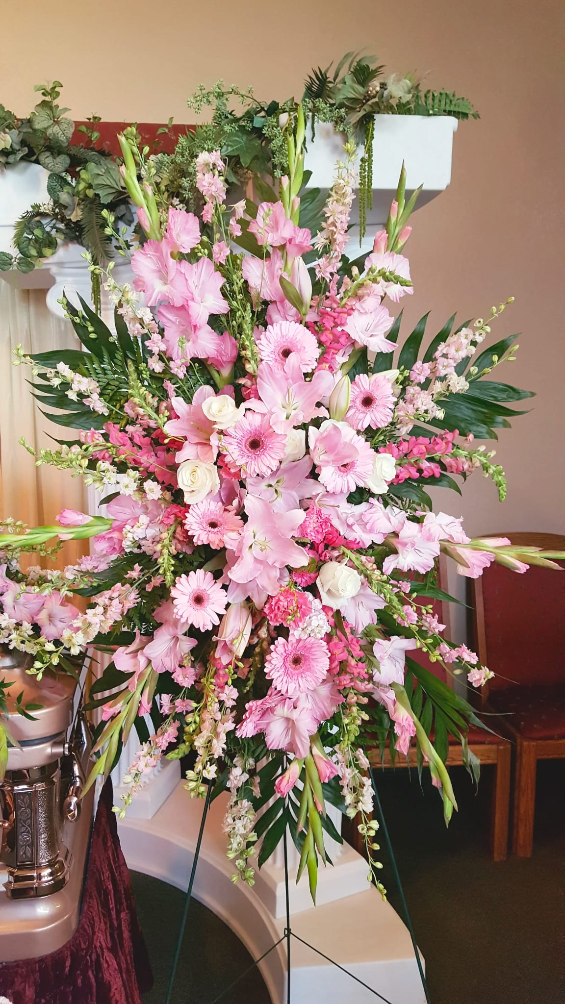 Easel Spray ES-19 Easel Spray ES-19 - Soft and feminine, this easel spray features an array of blush and pastel pink blooms including lilies, gladiolus, gerbera daisies, roses, stock, and snapdragons. Accented with delicate greenery and white highlights, this design offers a gentle and loving tribute to someone dearly cherished. Easel stand included for a beautiful display during the service.