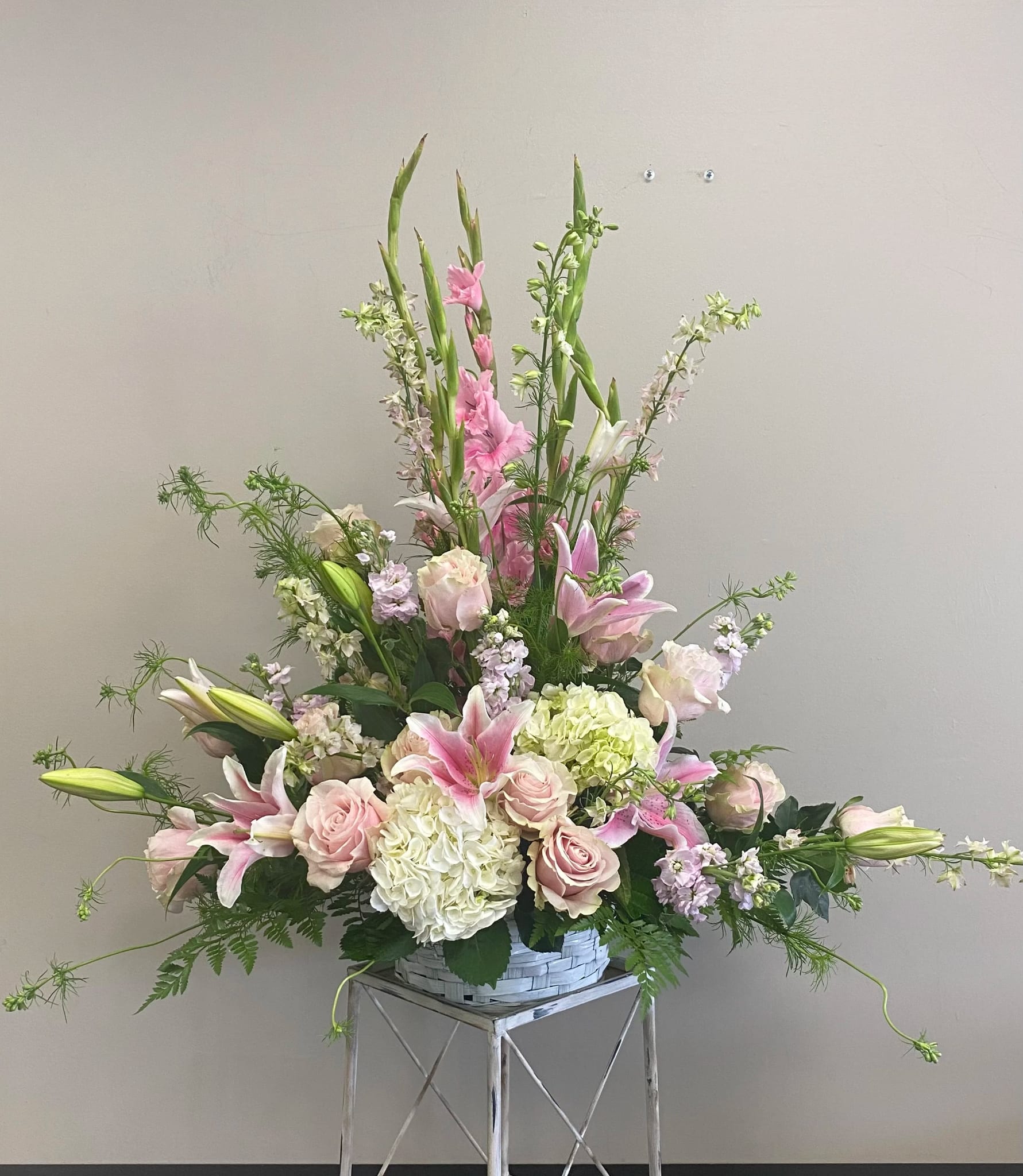 Ceremony Arrangement CV-19 Ceremony Arrangement CV-19 - Soft pink lilies, blush roses, white hydrangea, and gladiolus come together in this gentle ceremony arrangement designed in a woven basket. Its lush, pastel palette evokes tenderness and grace—an elegant tribute for a loved one remembered with love and light.