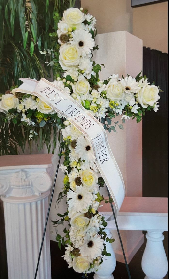 Cross CR-08 Cross CR-08 - This standing cross features a gentle blend of creamy white roses, bright gerbera daisies, and soft accents. A peaceful tribute that reflects purity, grace, and enduring love. Easel stand included. Ribbons available for an additional $10 per word.