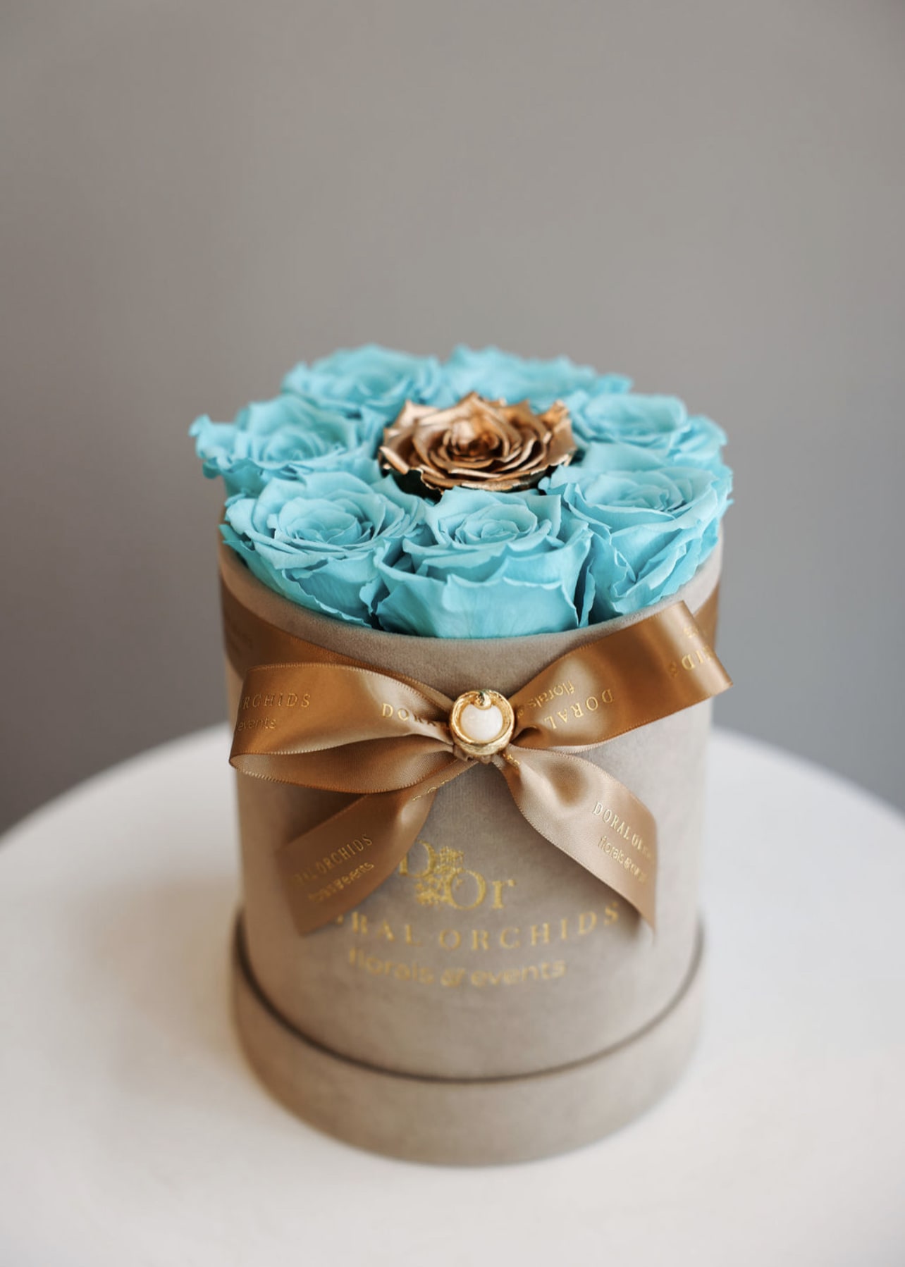 Lovely Roses - aqua &amp; gold, small ™ - Vivid aqua preserved roses designed to last 3 or more years form a stunning base for a single metallic gold rose centerpiece. Housed in a champagne velvet hatbox with gold ribbon, this natural long-lasting piece shines with bold sophistication.