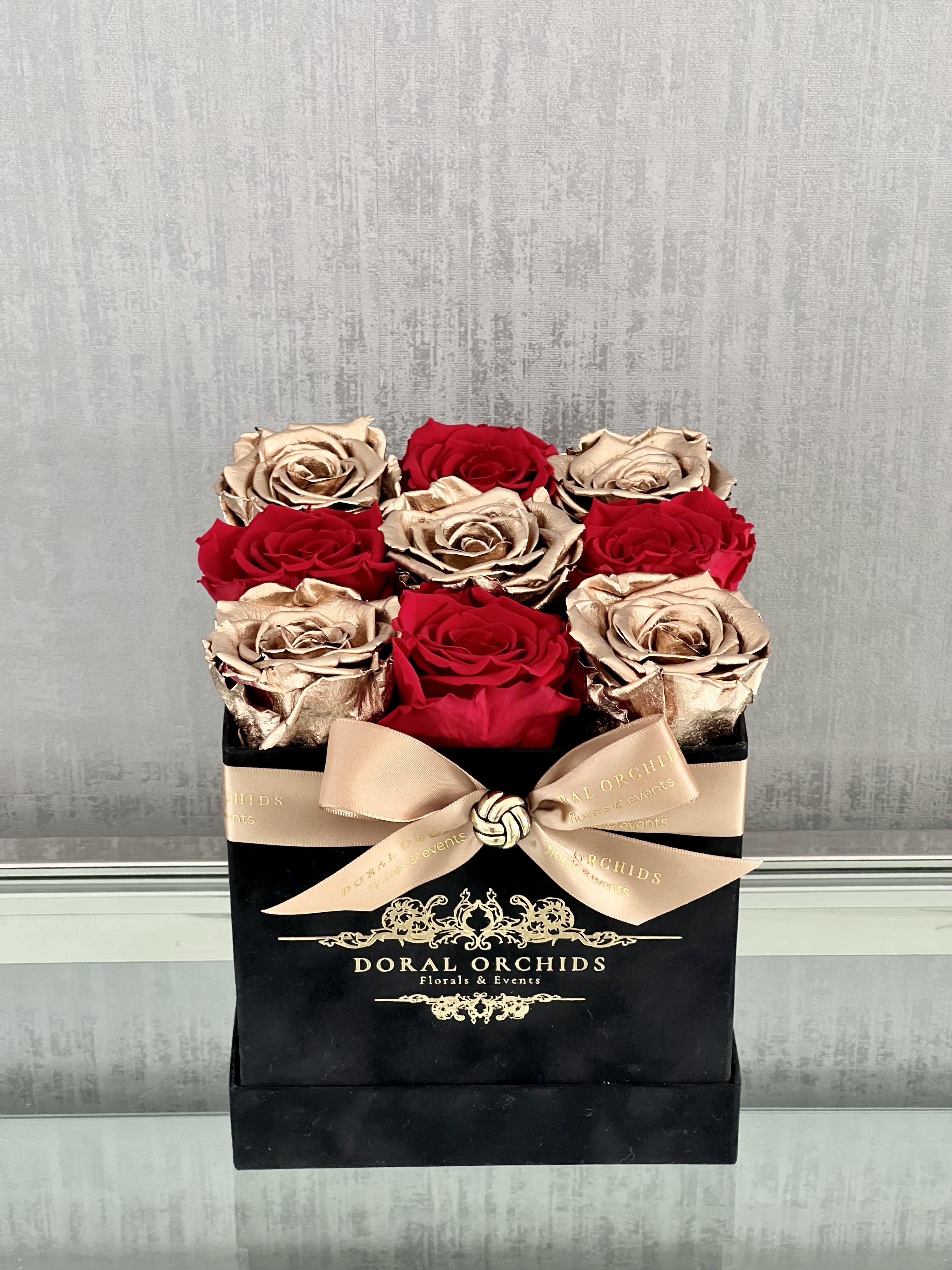 Royal Roses Red & Gold ™ Royal Roses Red & Gold ™ - Chic and modern, this preserved arrangement combines deep red roses with metallic gold roses in a black square hatbox, lasting 3 or more years.