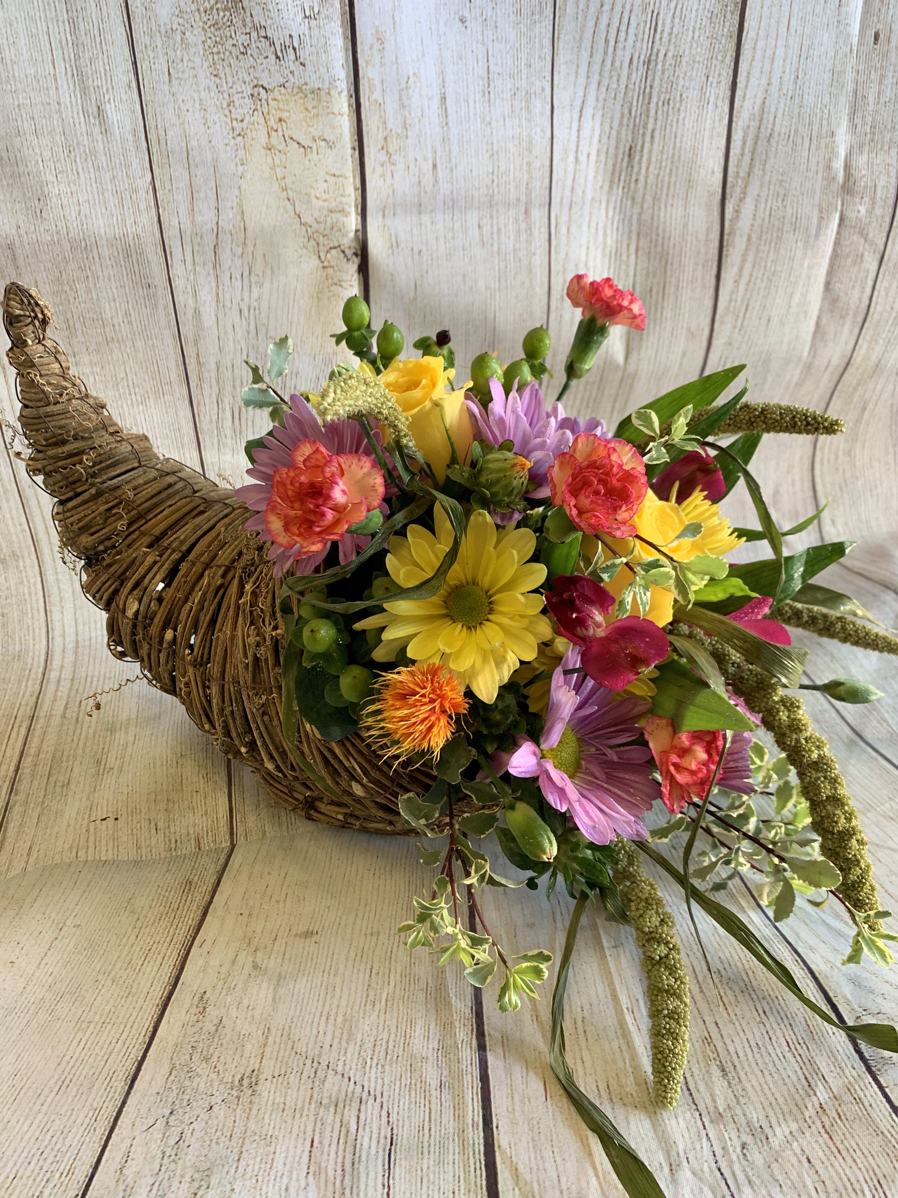 Cornucopia Cornucopia - Cornucopia: "an abundant supply of good things of a specified kind." Fresh flowers fill a keepsake wicker Cornucopia. (All designs are arranged as similar as possible. We promise to keep the same color, style, and overall theme with what Mother Nature generously blesses us with)