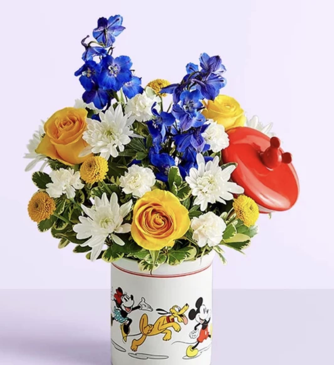 Disney Mickey Mouse &amp; Friends Cookie Jar- Baby Boy - Welcome the little prince with a gift full of character(s)! Part of our new Disney collection, this handcrafted bouquet is gathered in happy yellow, blue and white blooms and designed in our whimsical Mickey Mouse and Friends cookie jar, featuring iconic animations. Great as a keepsake container or for keeping treats, it’s an adorable way to celebrate the littlest Disney fan and family.