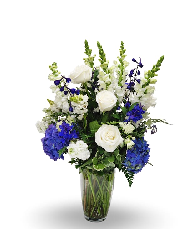 Blue Elegance Blue Elegance - Blue Elegance is a graceful arrangement designed in a clear glass vase with a refined mix of white and blue blooms. Featuring rich blue hydrangea, elegant white roses, striking delphinium, snapdragons, and lush greenery, this design brings a timeless sense of beauty and sophistication. Perfect for both celebrations and moments of remembrance, it offers a classic expression of style and grace.