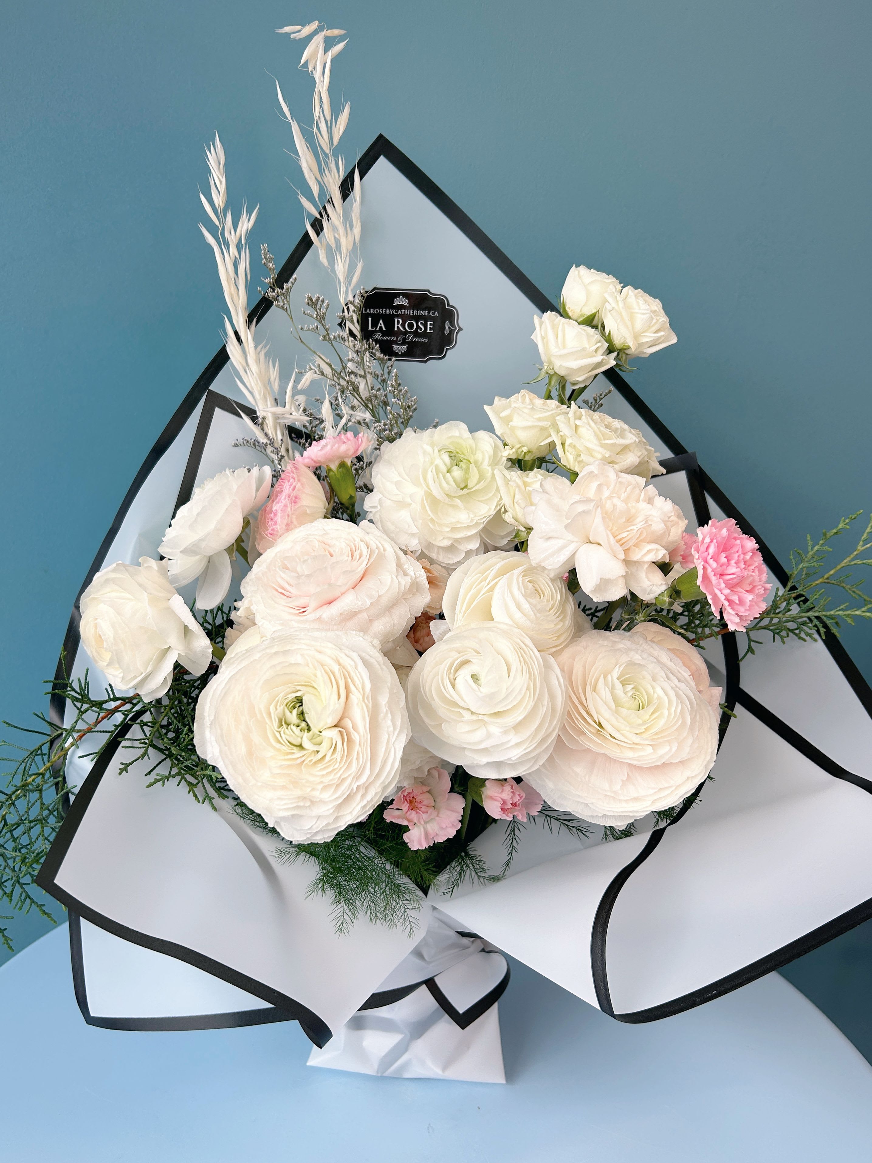 White Vase Bouquet - Elevate your space with the timeless elegance of our White Vase Bouquet. Featuring a stunning arrangement of fresh white blooms—such as roses, lilies, and other seasonal flowers—this bouquet exudes purity and sophistication. Paired with lush greenery and arranged in a designer’s choice vase, it’s perfect for weddings, special events, or minimalist home décor. Each bouquet is elegantly packaged to enhance its modern, clean aesthetic. Add a touch of elegance to any occasion with this chic, all-white floral arrangement.  standard size:  14-16 florals deluxe size:  20-22 florals premium size:  26-28 florals