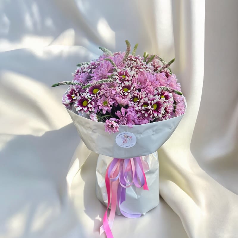 Blush Elegance Wrapped Bouquet #72 - The Blush Elegance Wrapped Bouquet features a delightful assembly of pink chrysanthemums, wrapped in tasteful, high-quality paper. This arrangement exudes a soft, romantic charm, perfect for occasions such as birthdays, anniversaries, or just to brighten someone's day. The vibrant pink hues of the chrysanthemums symbolize love and admiration, making this bouquet a heartfelt and elegant gift for any special moment.