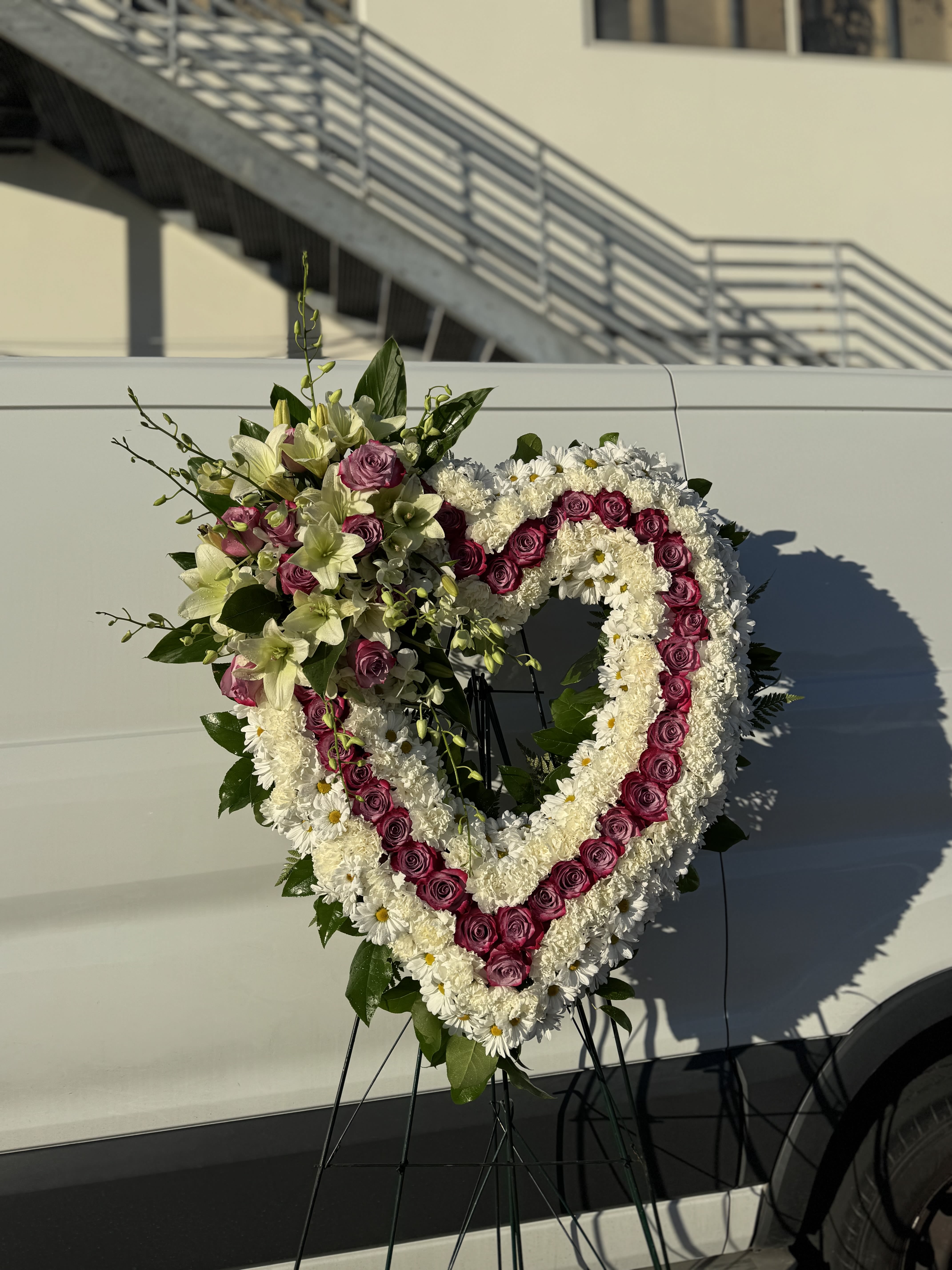 Heart Wreath #12 Heart Wreath #12 - A standings flower arrangement for a funeral service is a heartfelt tribute designed to honor and celebrate the life of the deceased. These arrangements are typically displayed on an easel or stand, making them highly visible and a central part of the memorial decor.