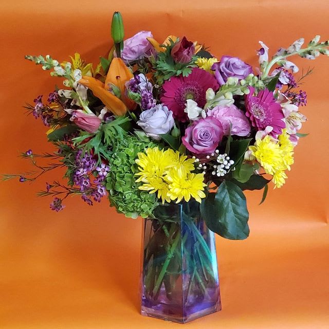 A Bright Mix Vase Arrangement  - A bright mix of seasonal blooms in a designers choice glass vase. Perfect for any special   celebration to brighten any space.  