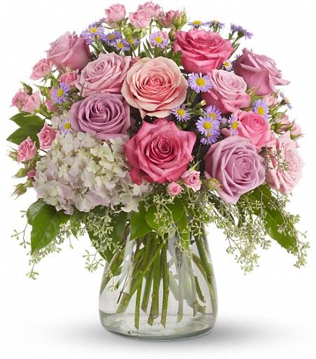  Your Light Shines - This softly elegant gesture of condolence and affection honoring the memory of a life well-lived is a gentle touch during a difficult time. Lavender and pink flowers such as roses, hydrangea, monte casino asters, eucalyptus and salal are arranged in a clear glass hurricane vase. 
