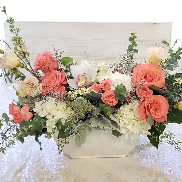 Soft Embrace  - A gorgeous peachy, coral and white floral arrangement with dusty miller, a variety of eucalyptus  tulips roses, spray roses, larkspurs orchids, and other in season blooms.  Perfect to show your love.  