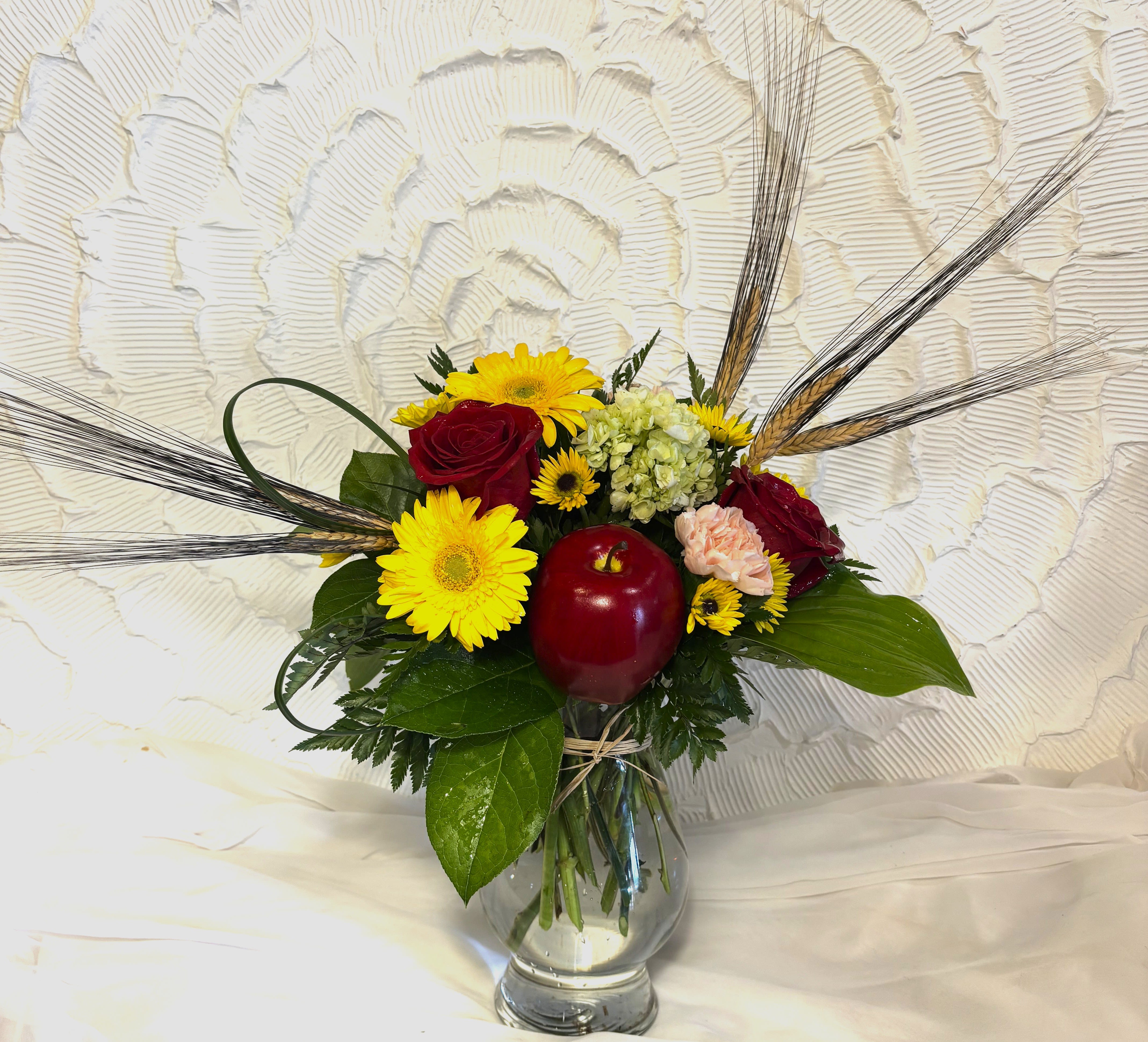 An Apple A Day An Apple A Day - This crisp arrangement is full of red and yellow flowers including, roses, viking, hydrangeas, carnations, gerbera daisies, wheat, grass loops and a big red apple to tie it all together. A perfect arrangement to show your teacher your appreciation.